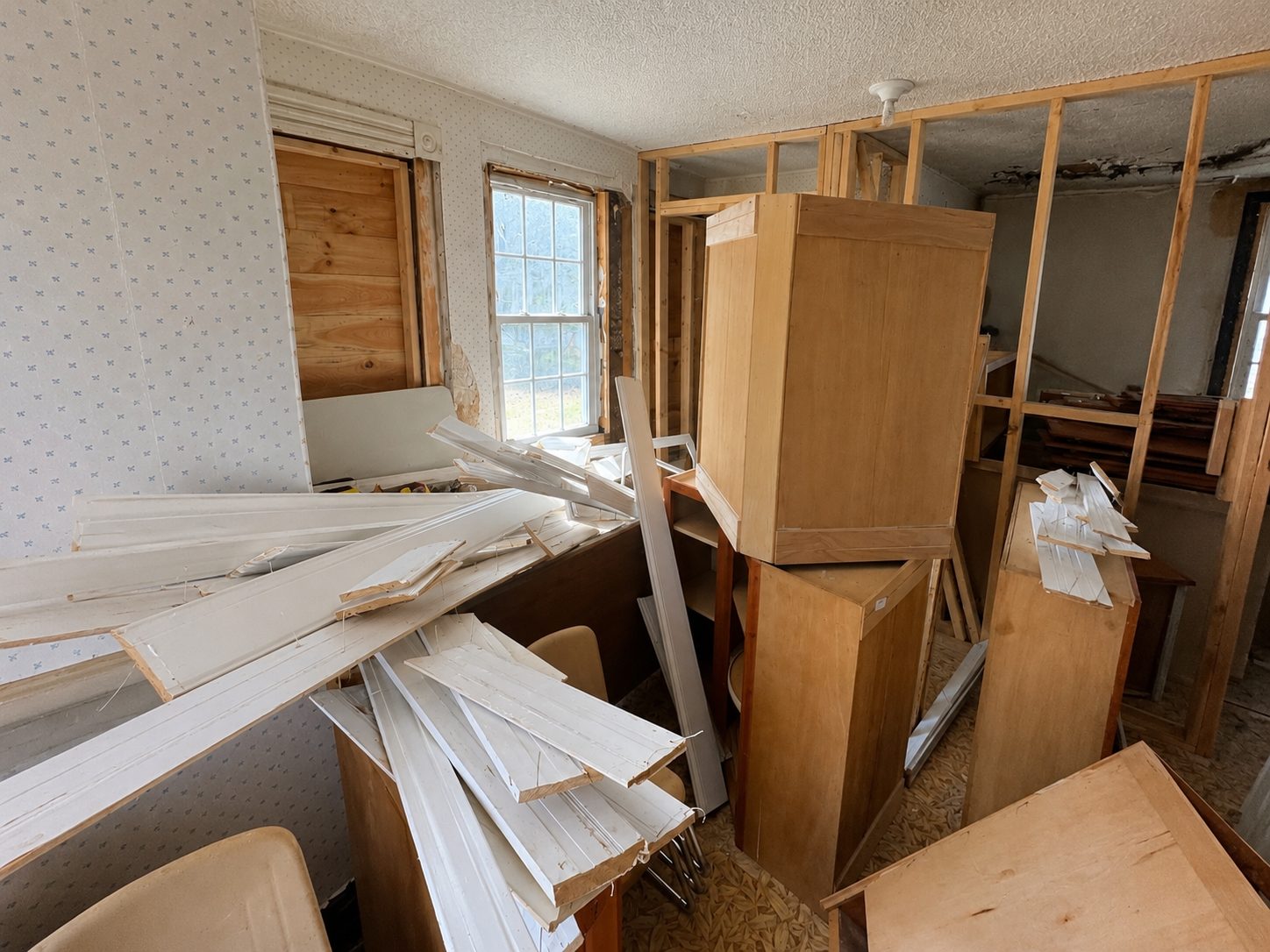 The old kitchen stripped back, cabinets stacked in the middle of the room and stud walls exposed