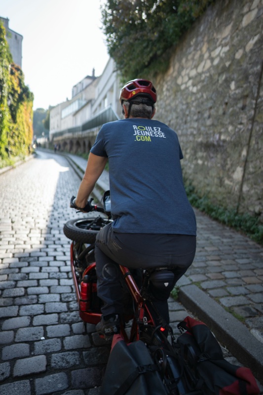 Réparateur Roulez Jeunesse à vélo cargo dans une rue de Lyon