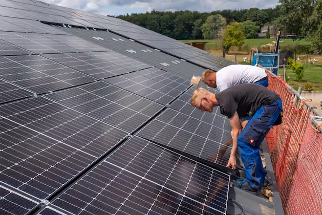 Handwerker installieren Solarpanele auf einem Dach
