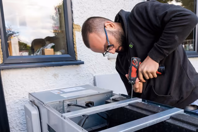 Handwerker installiert eine Klimaanlage an einer Hauswand