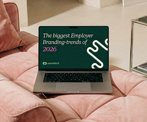 Laptop on a pink sofa displaying the cover of weselect's e-book "The Biggest Employer Branding Trends of 2026."
