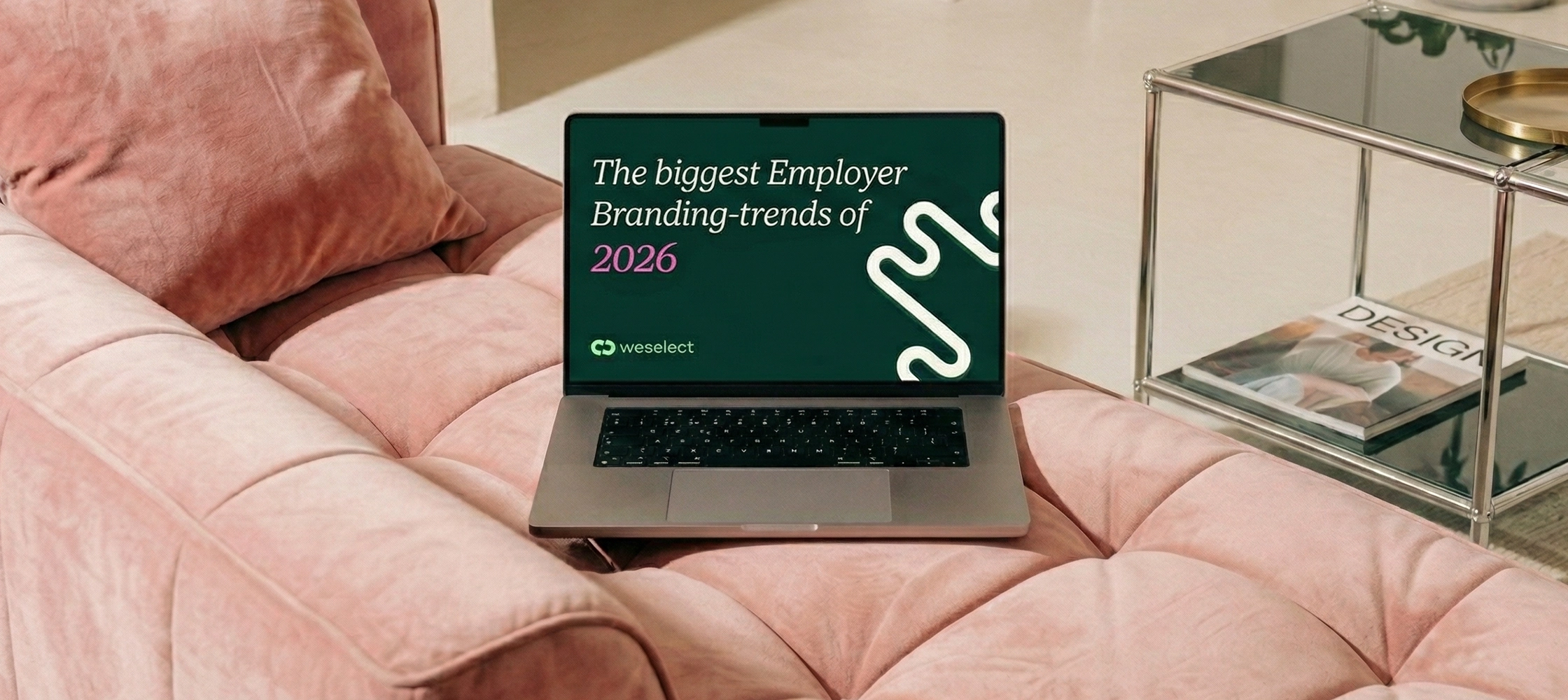 Laptop on a pink sofa displaying the cover of weselect's e-book "The Biggest Employer Branding Trends of 2026."