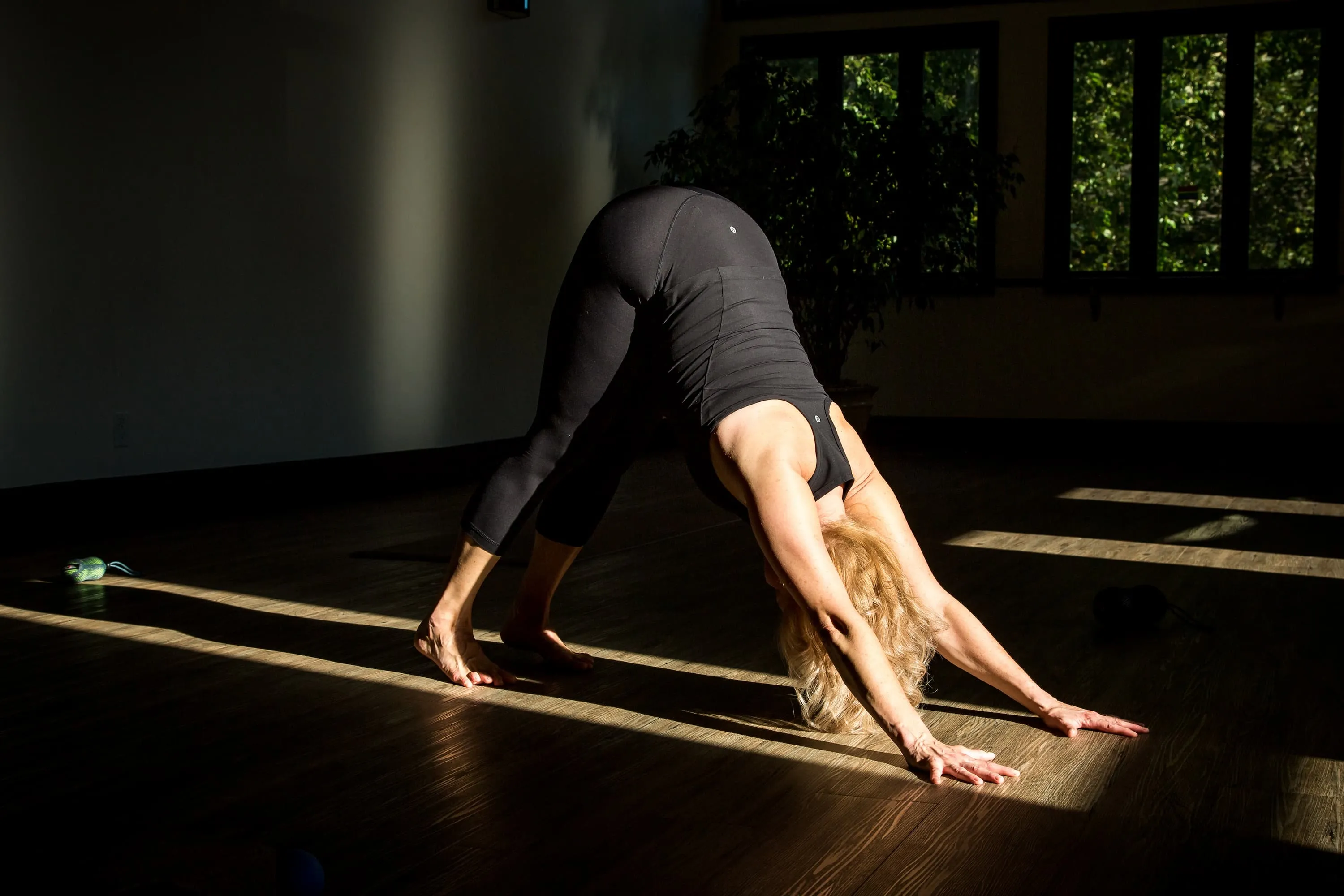 Sheri dressed in black doing a downward facing dog pose.