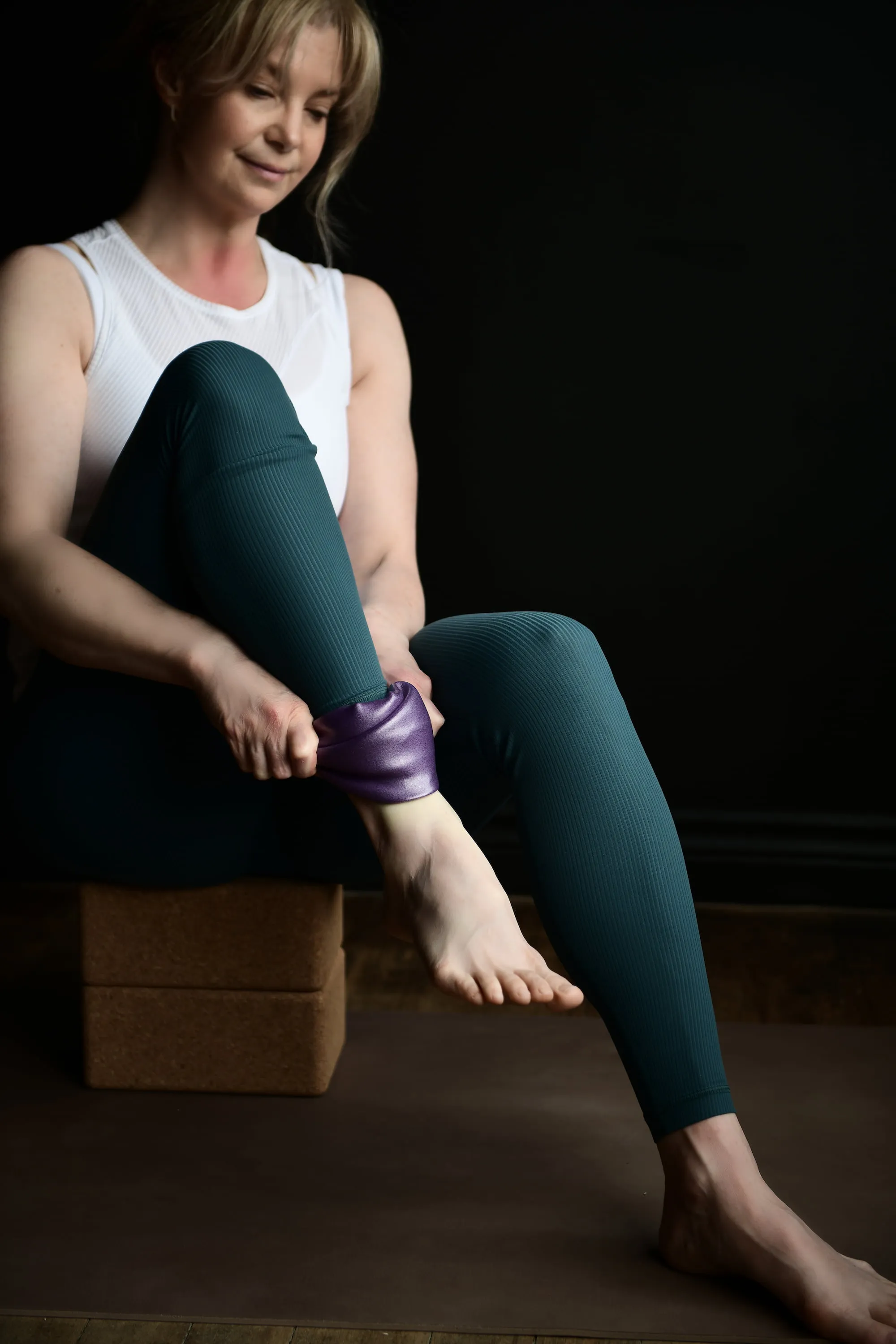 Sheri seated in chair lifting one foot, with strap around it
