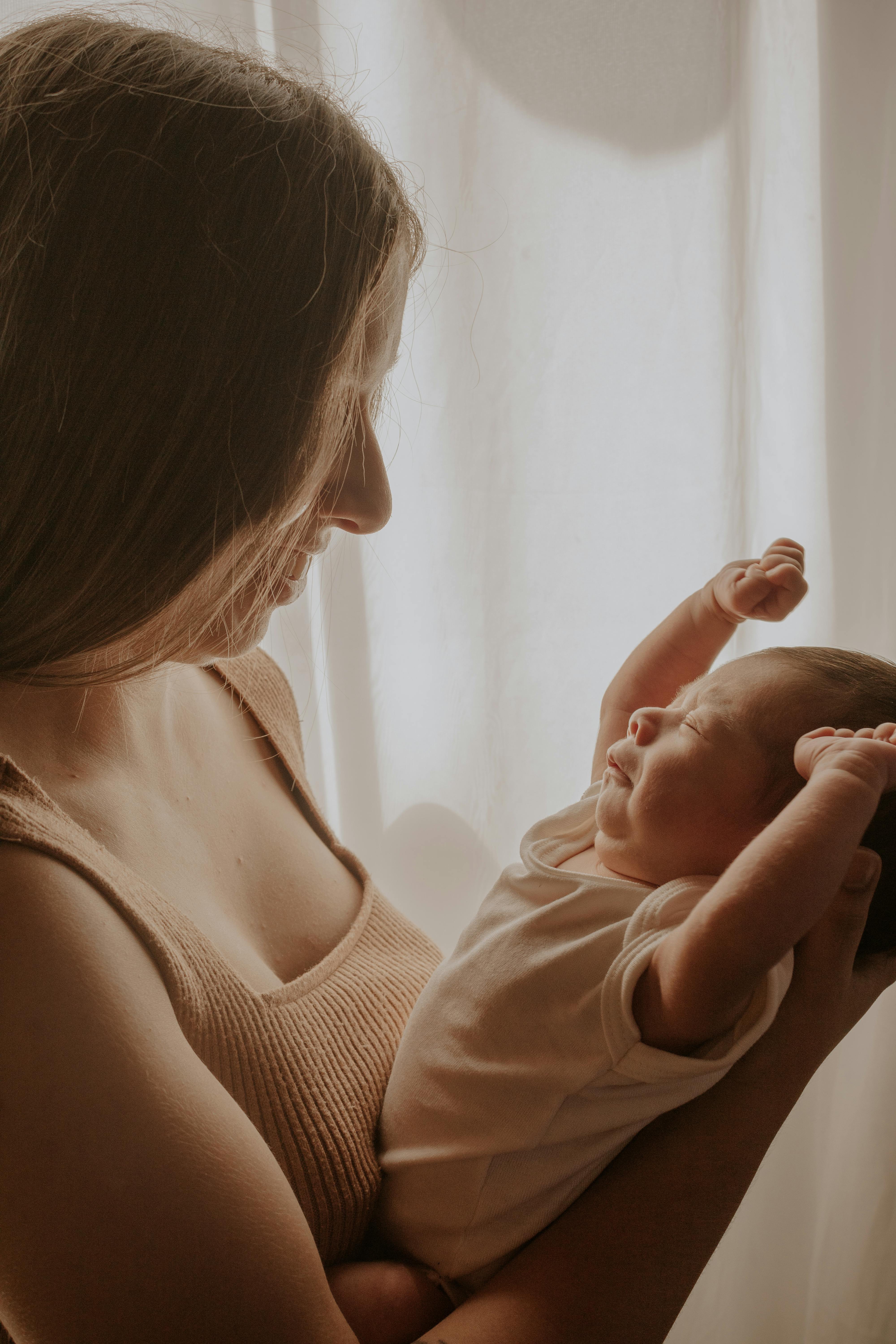 Infant with eczema on arms being comforted by mother holding natural balm 