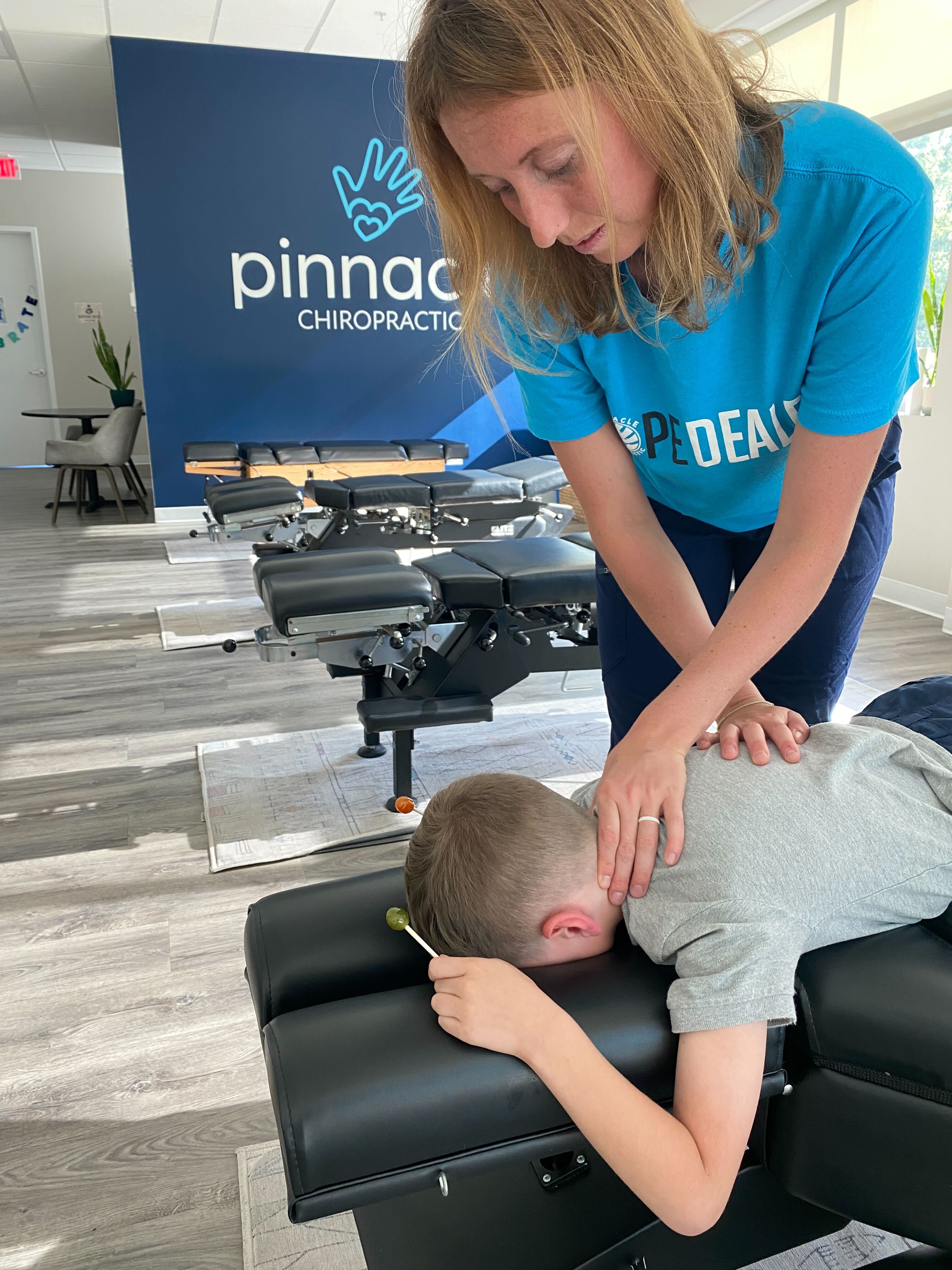 A kid is left smiling with a lollipop after a chiropractic adjustment at Pinnacle Chiropractic.