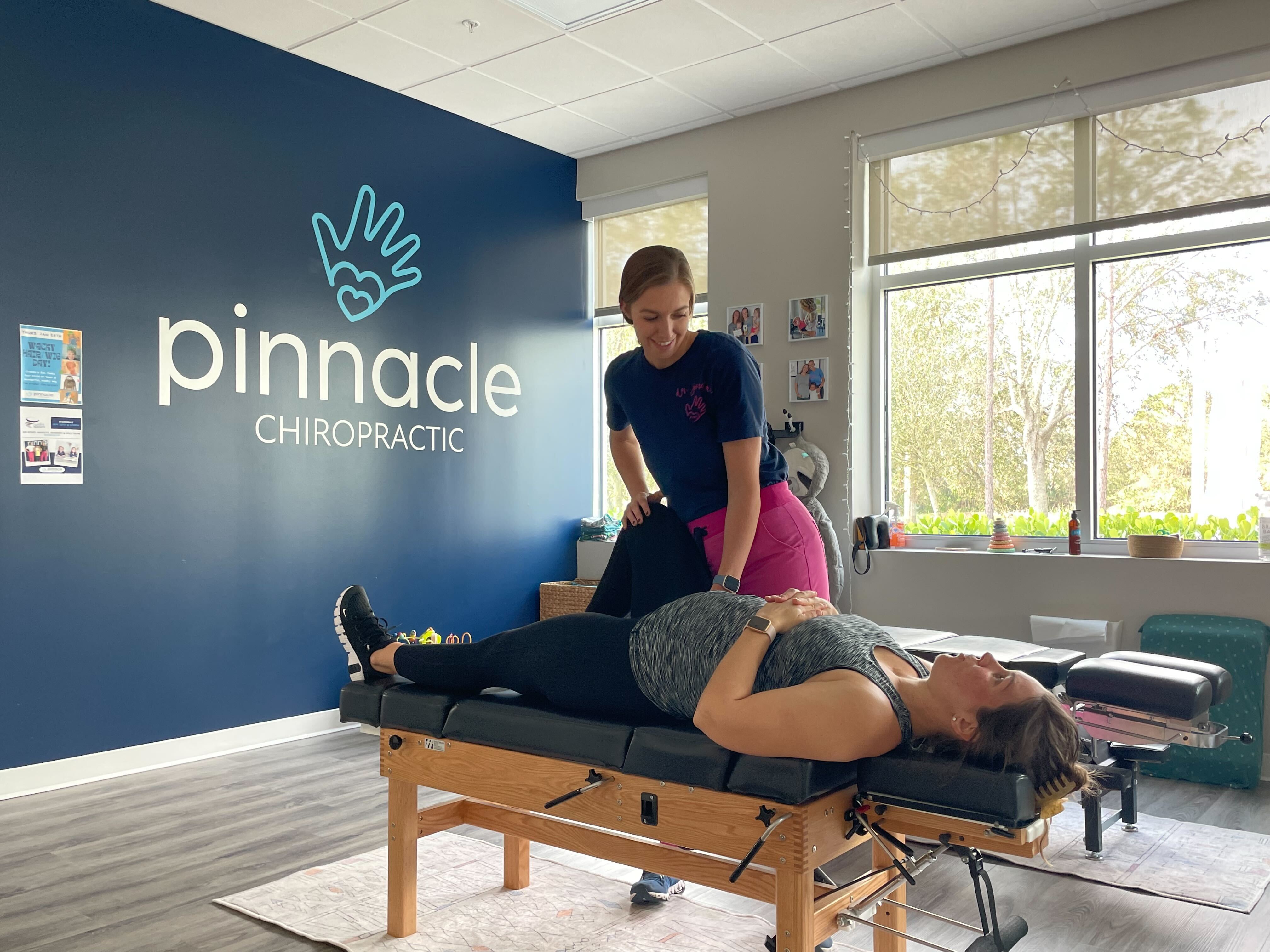 Female chiropractor performing adjustment on patient in modern clinic for back pain relief and holistic chiropractic care.