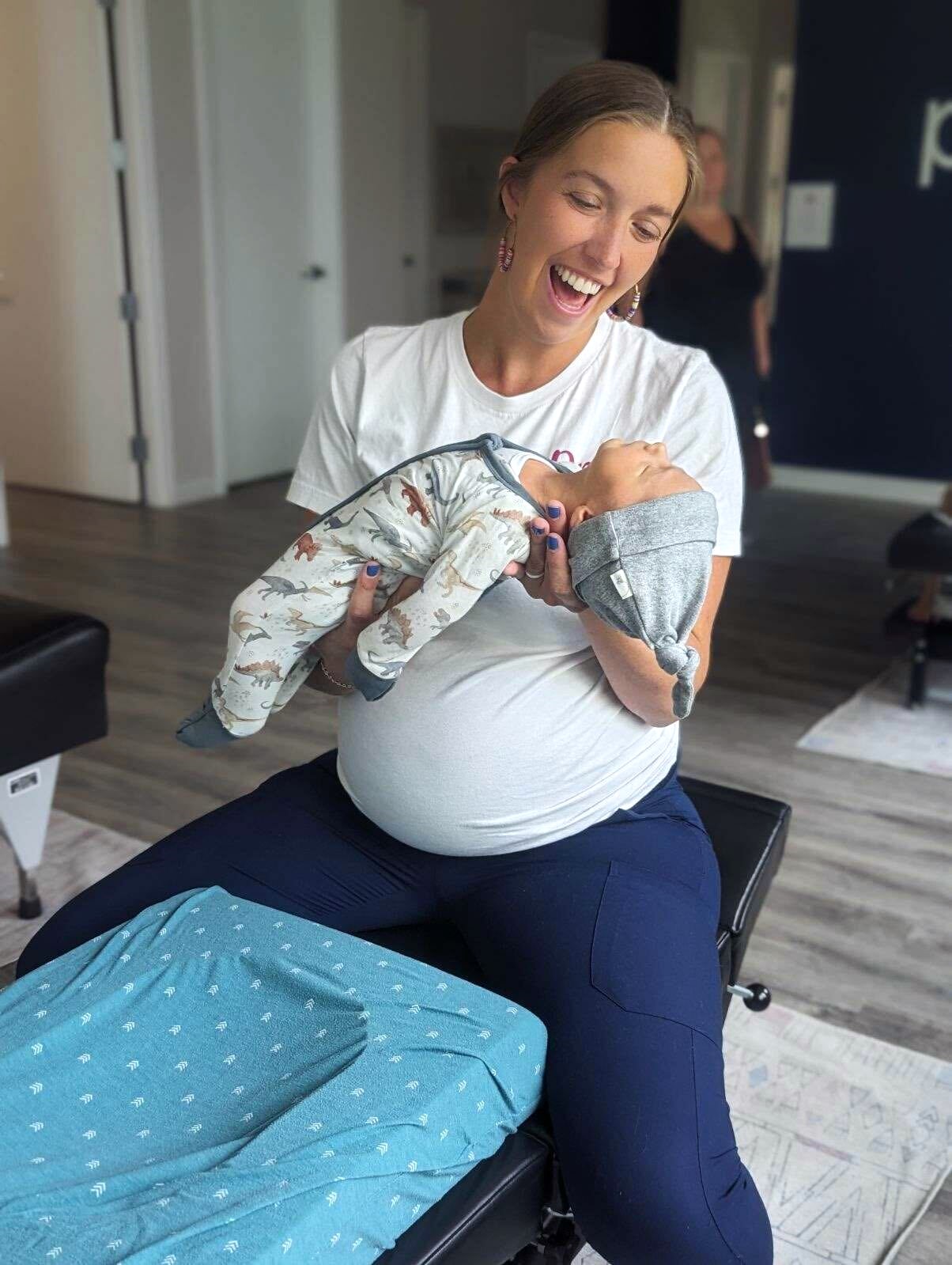 Young mother and infant during a joyful chiropractic session promoting infant care and family wellness in a modern clinic.