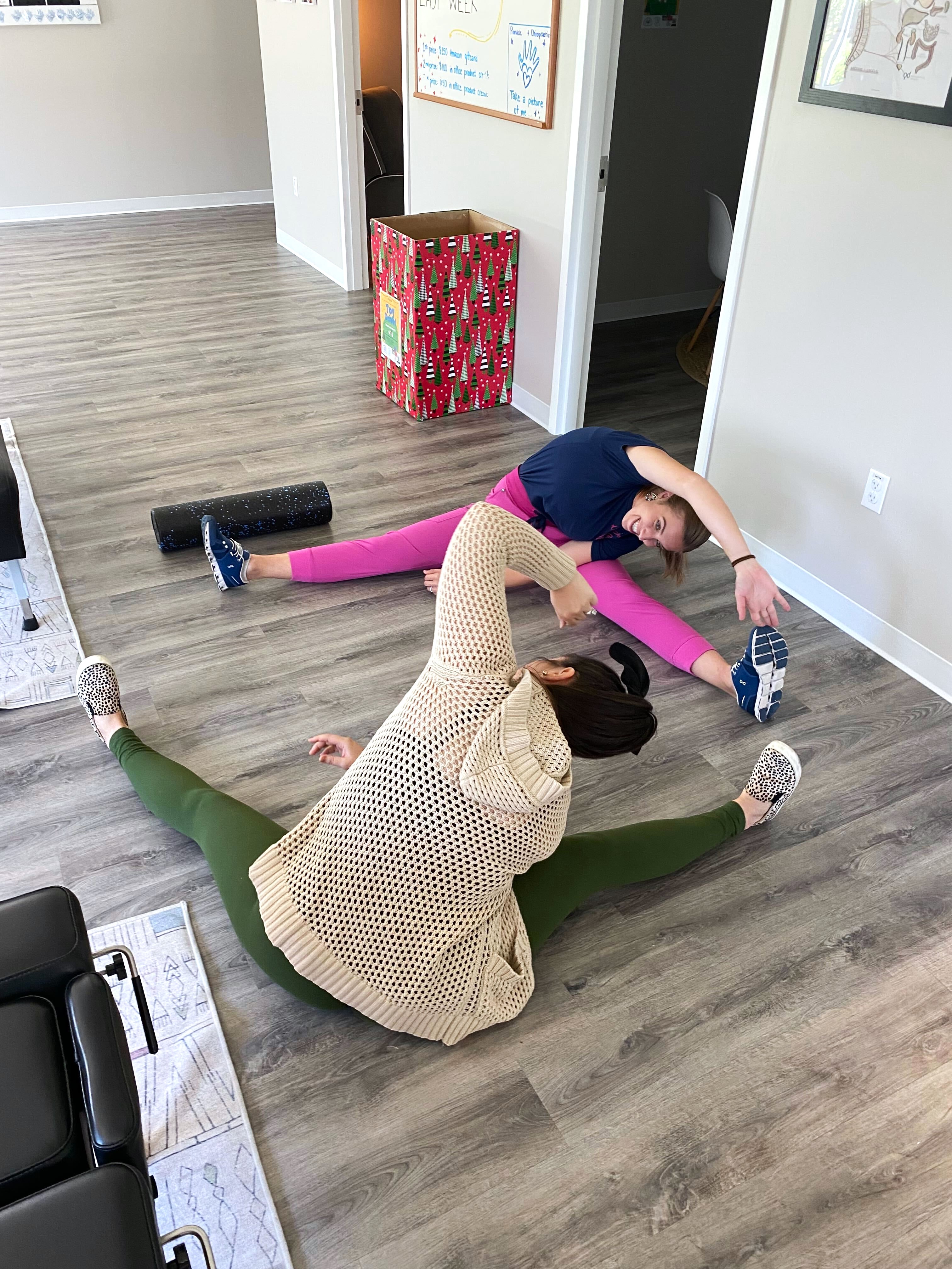 Young woman and child doing stretching exercises with foam roller in bright room, promoting prenatal comfort and family we...