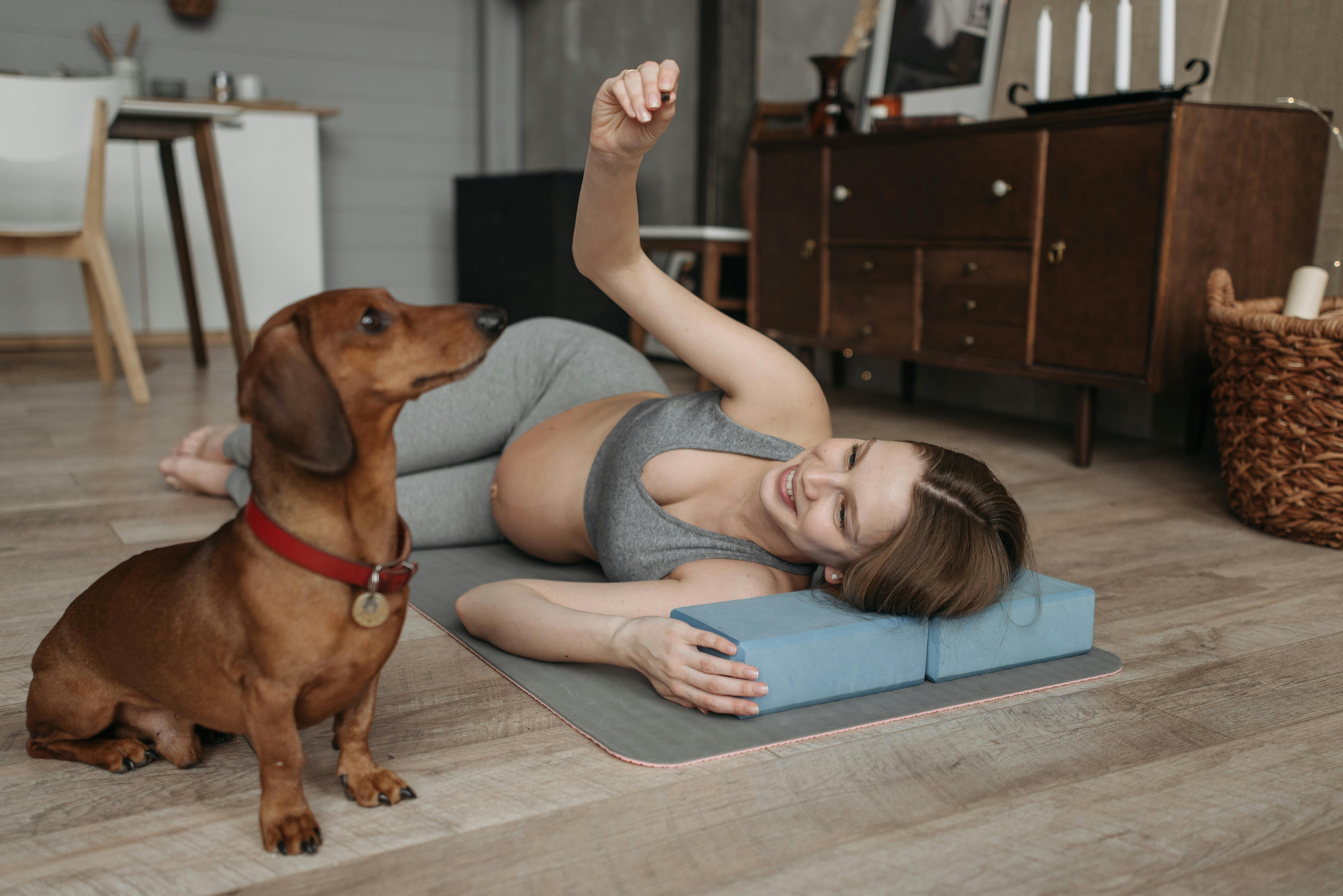 Pregnant woman laying on floor with her dog.
