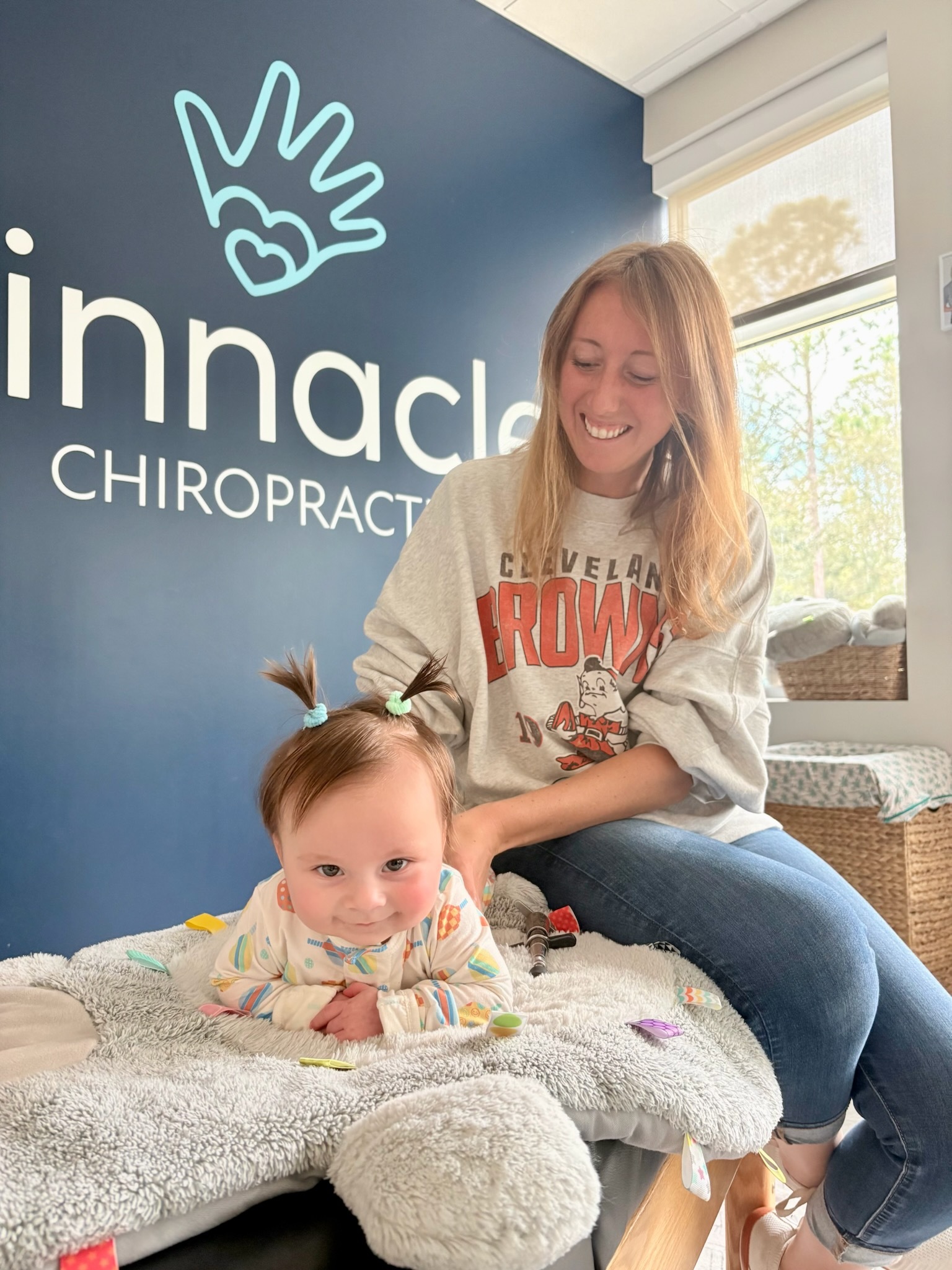 Infant receiving gentle chiropractic adjustment with light pressure, demonstrating safe and calming pediatric chiropractic care.