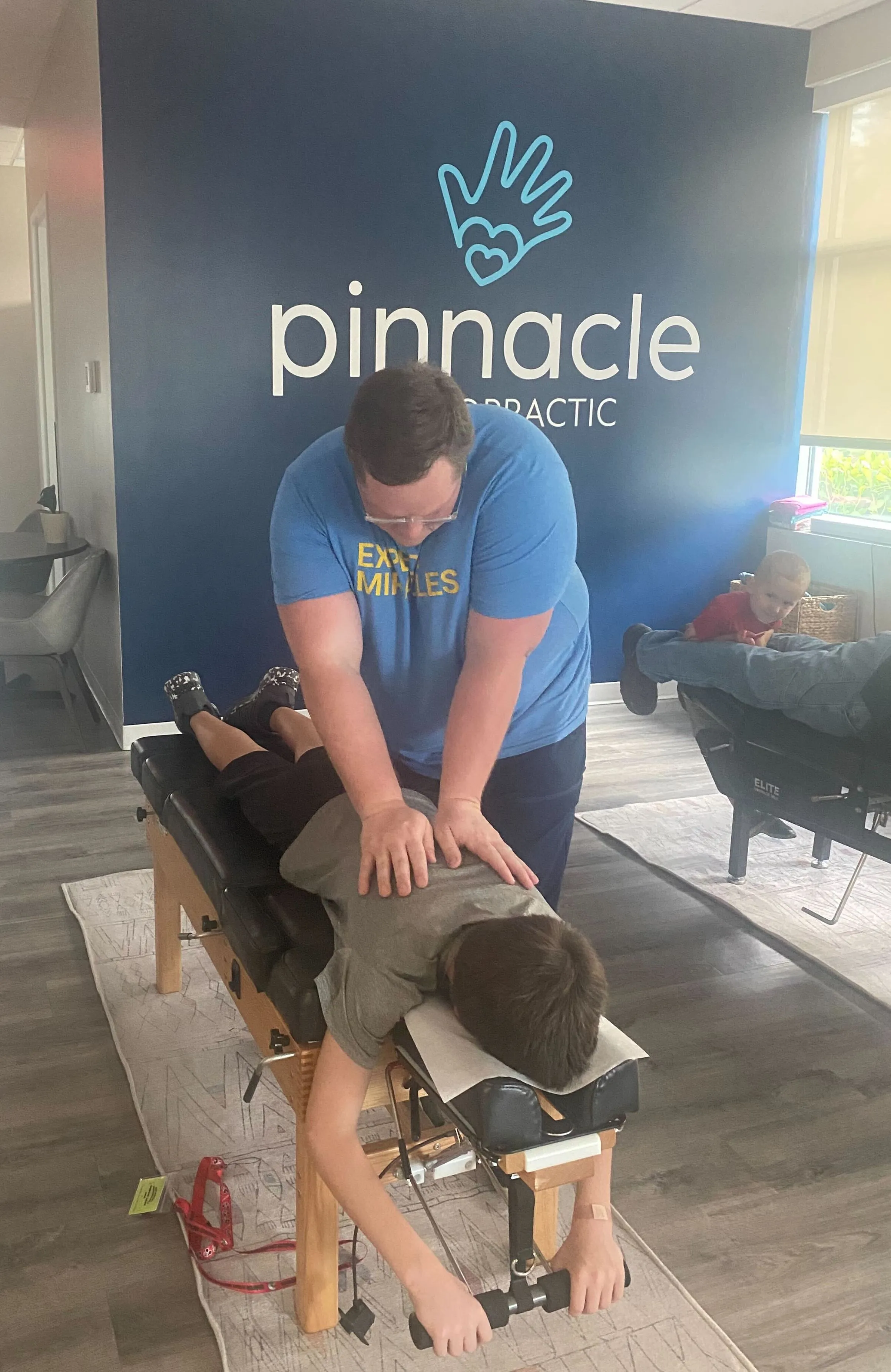 A chiropractor adjusting a school-age child's back at Pinnacle Chiropractic
