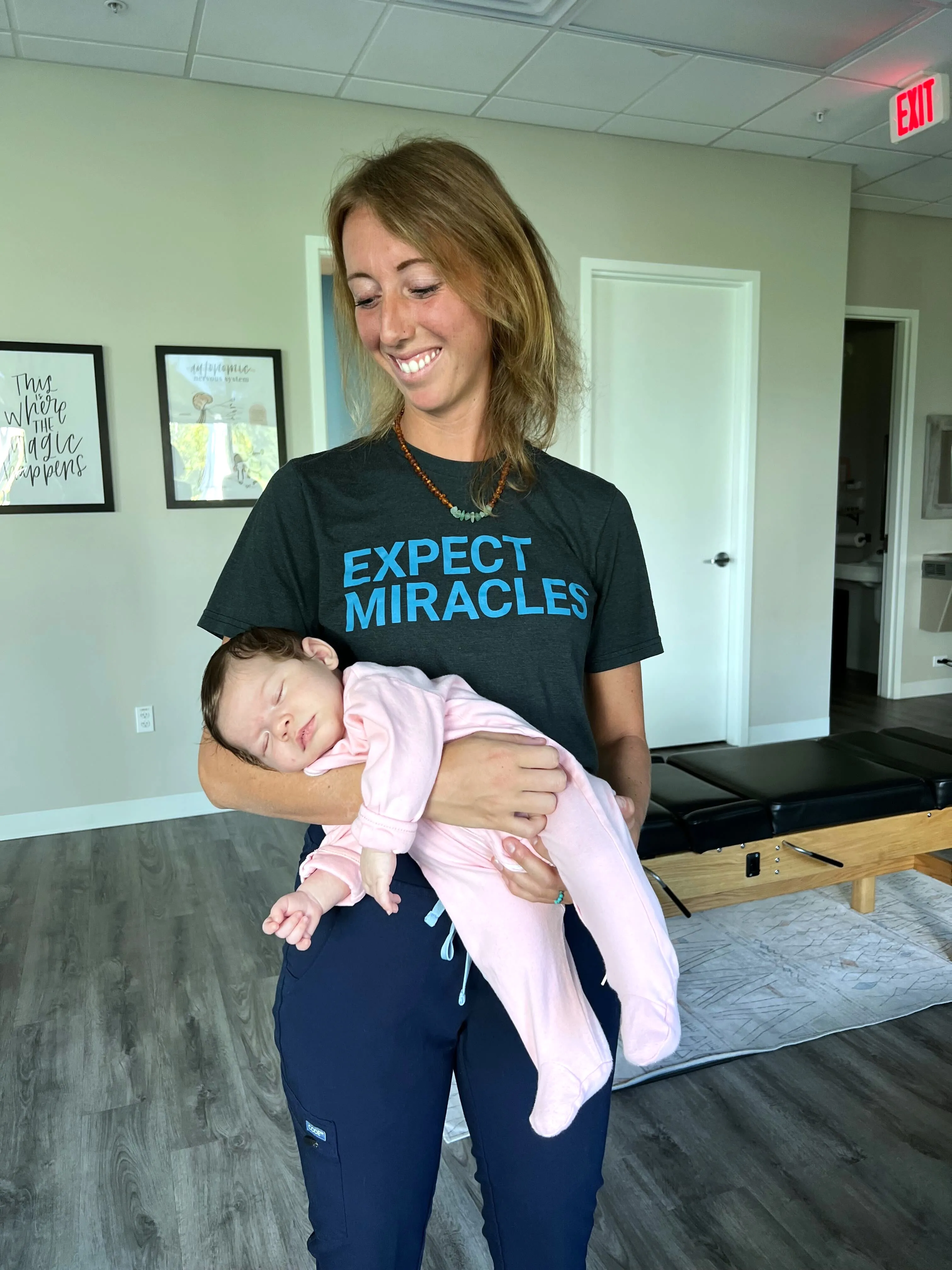 A Pinnacle Chiropractic team member gently holding a sleeping infant