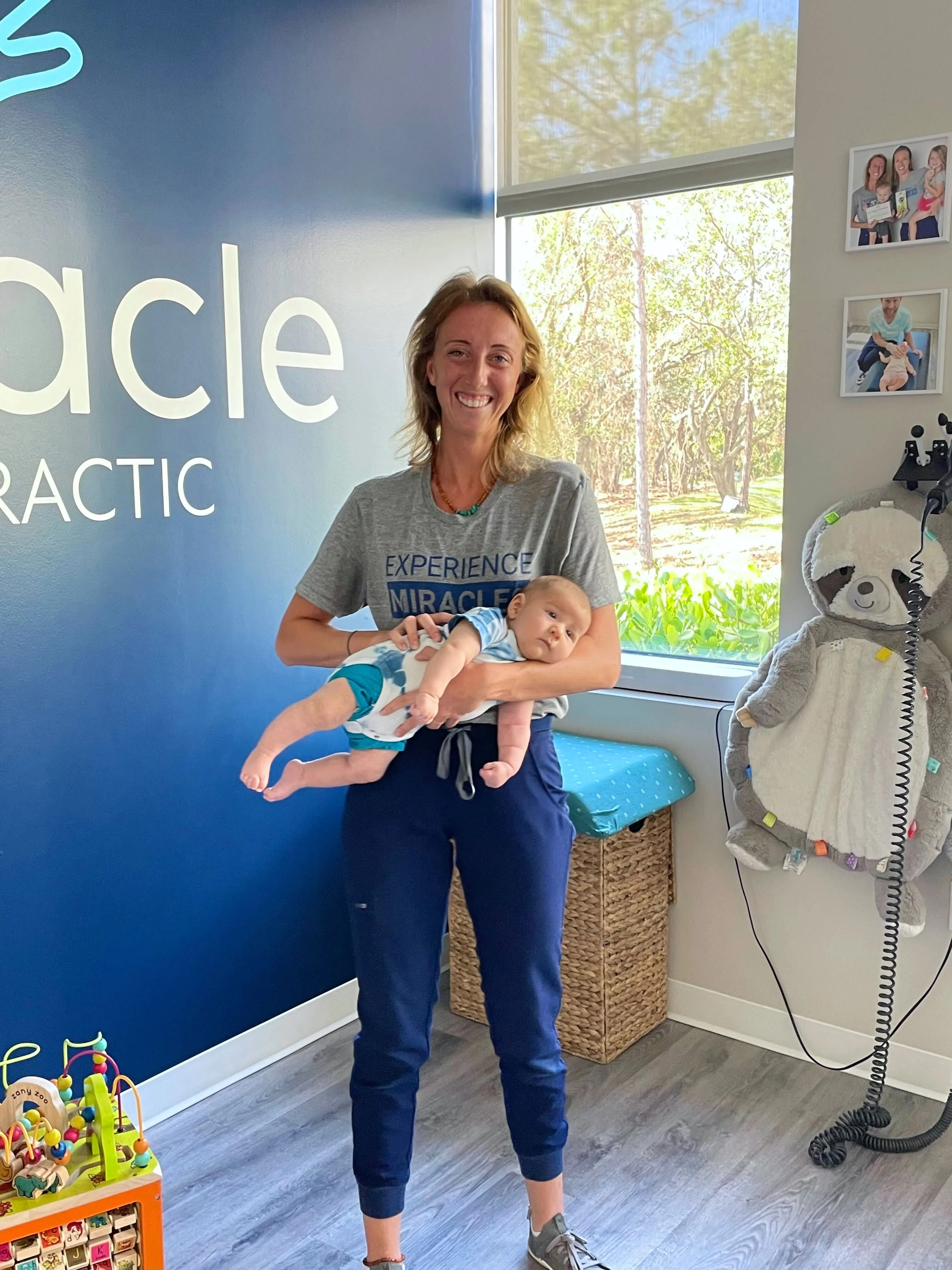 A Pinnacle Chiropractic team member holding a baby by a sunny window