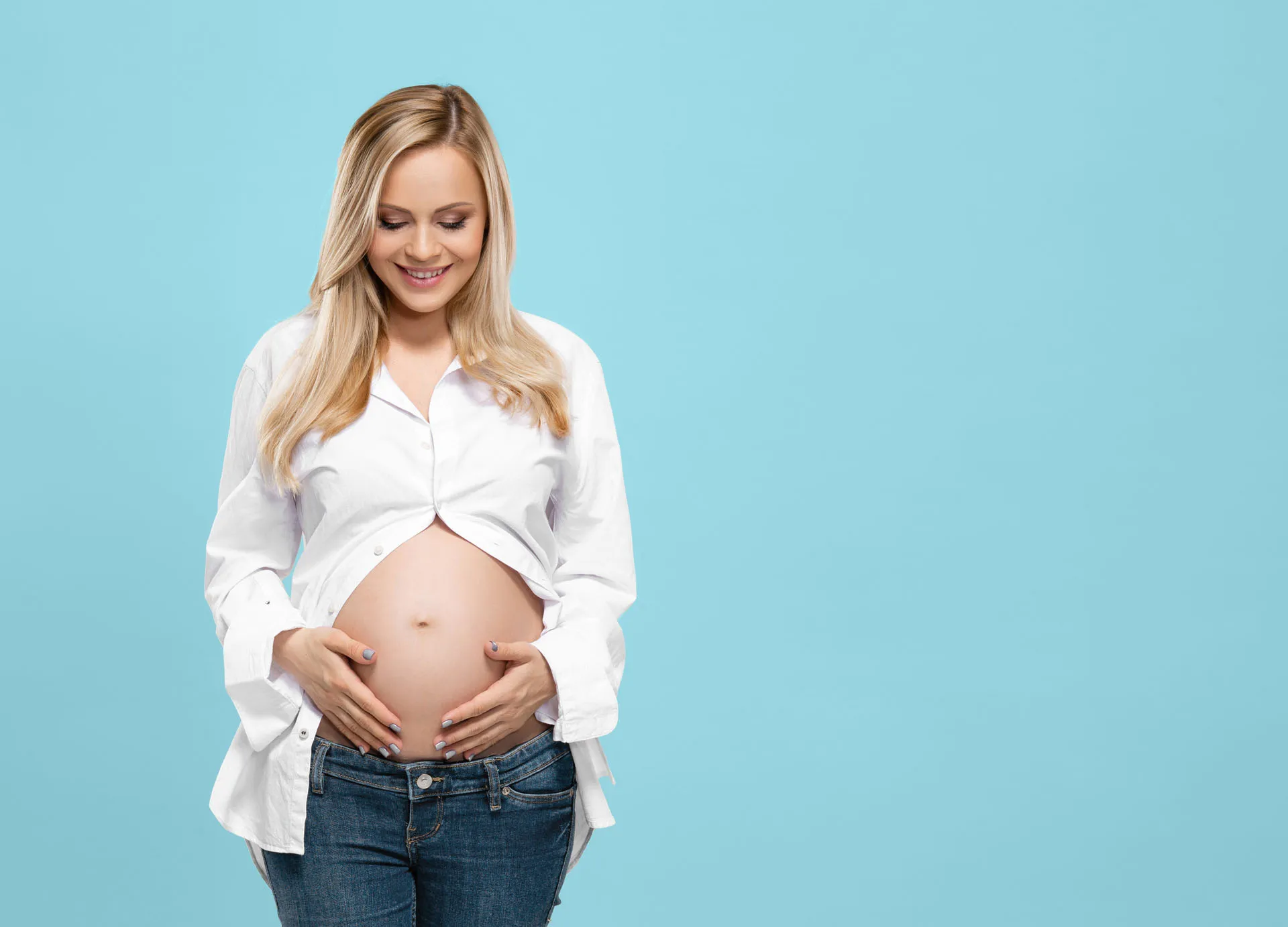 Pregnant woman smiling, holding her belly