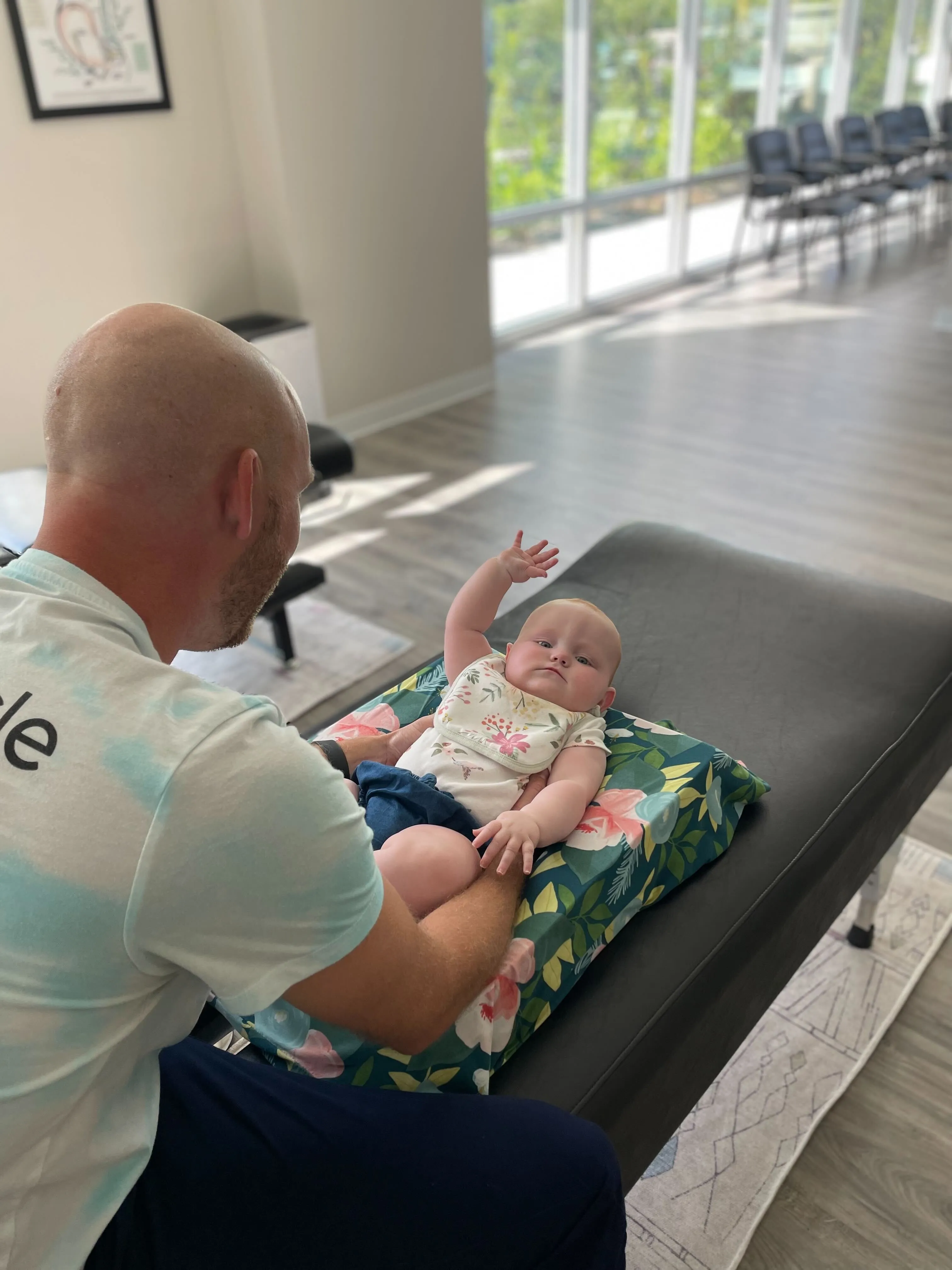 Parent gently repositioning baby during tummy time to help with flat head shape