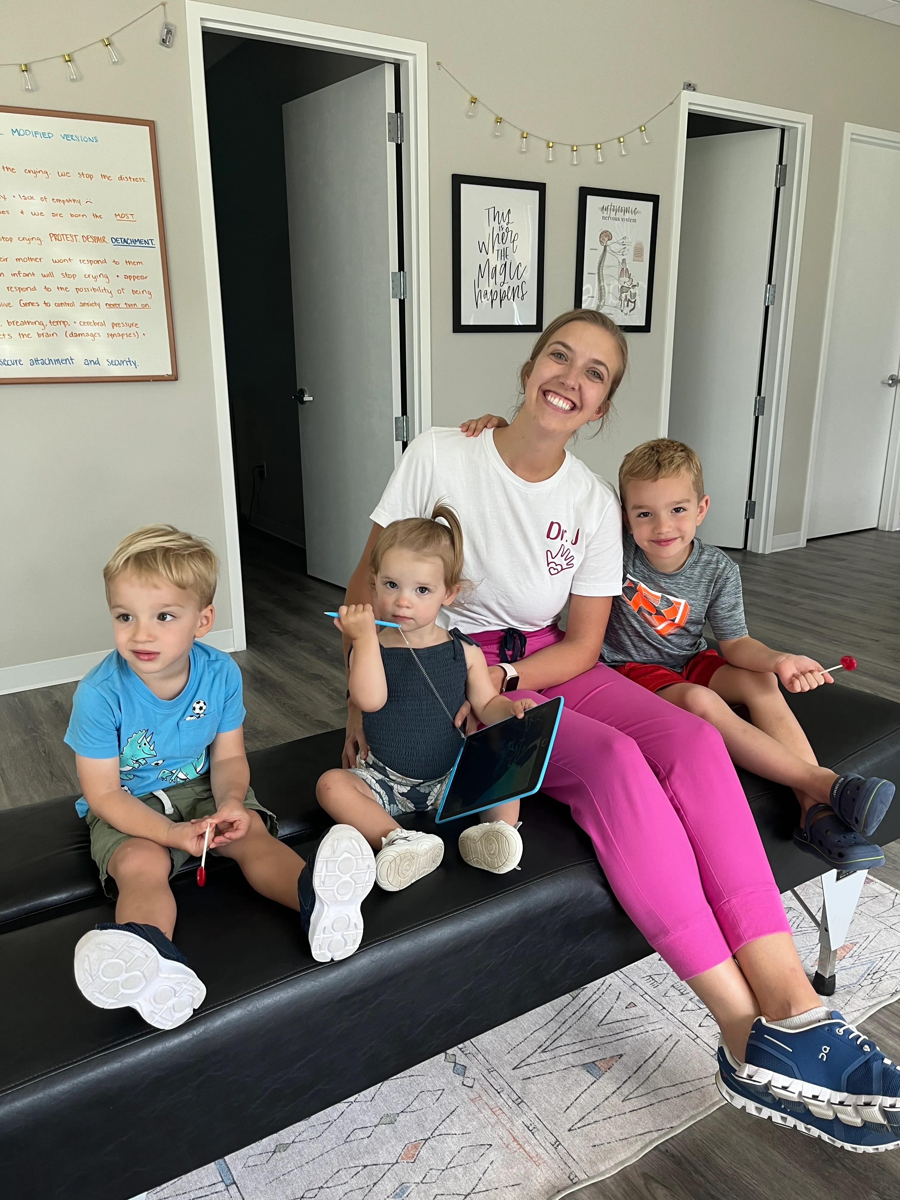 A Pinnacle Chiropractic staff member sitting with three young children in the office