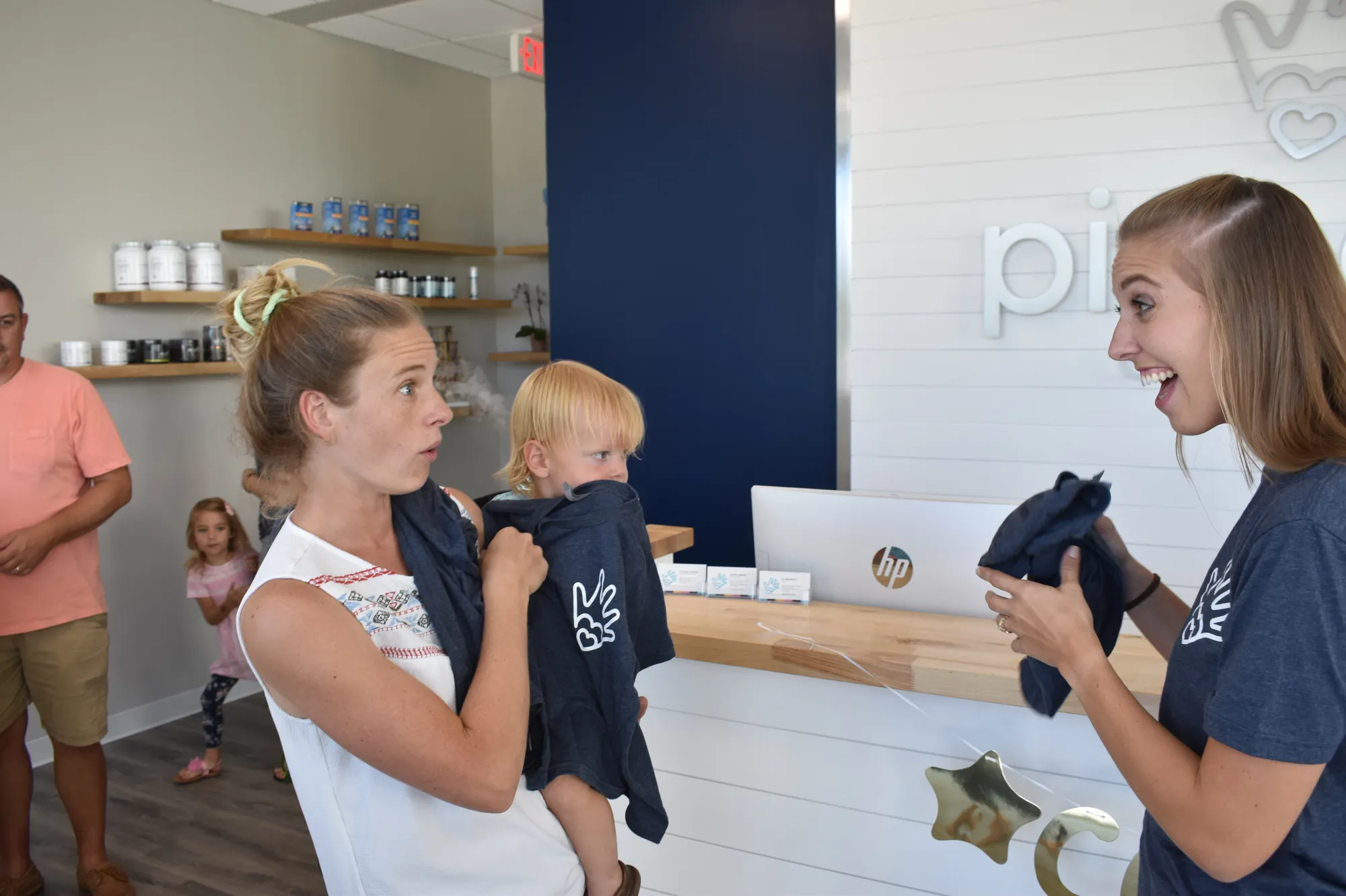 A mother holding her toddler at the Pinnacle Chiropractic front desk