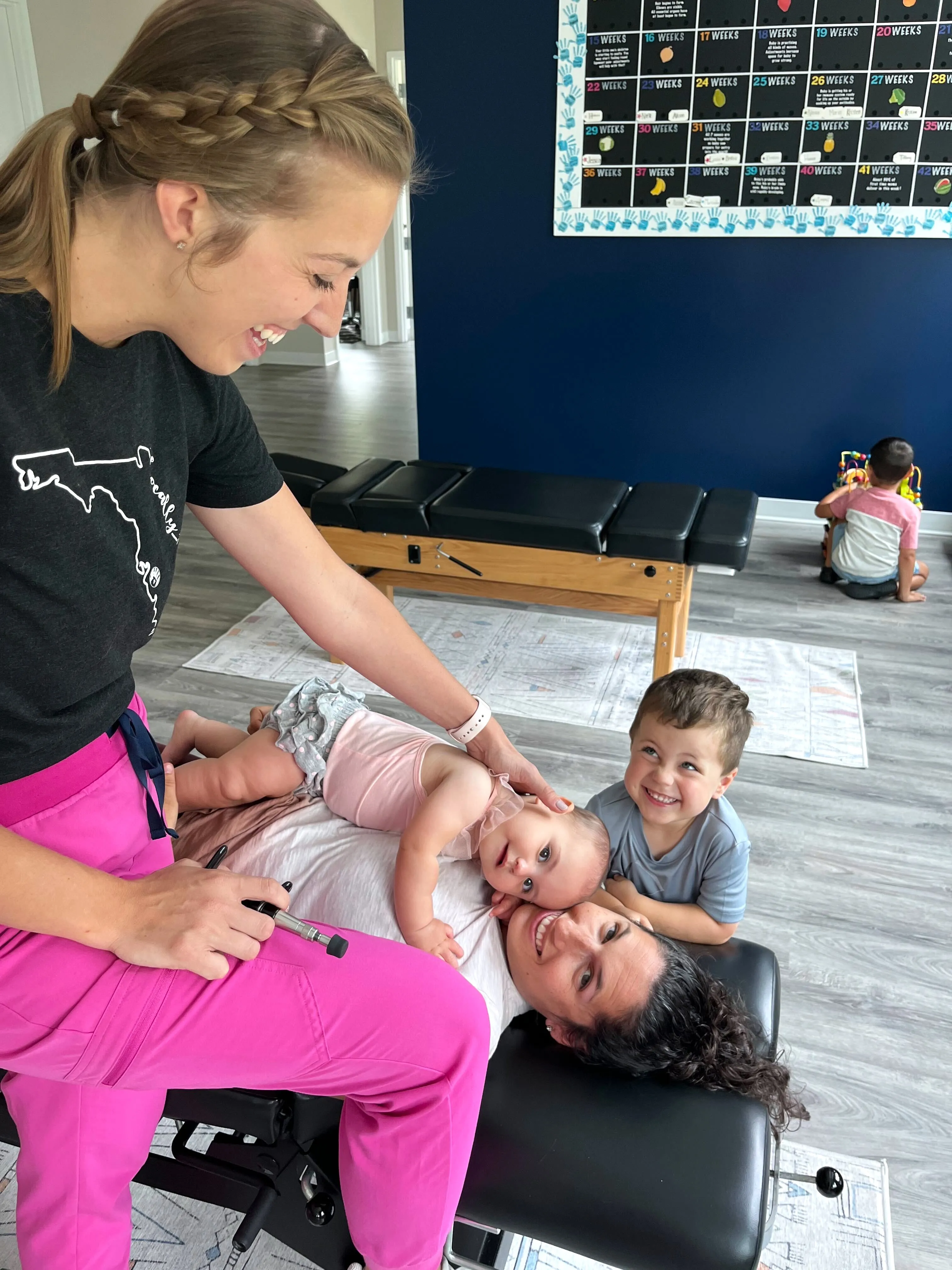 A Pinnacle Chiropractic team member with a baby, a toddler, and a parent during a visit
