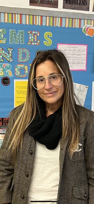 Jennifer Lerman faculty member standing in front of classroom bulletin board