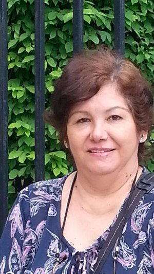 Nilda Morales smiling outdoors in front of green foliage
