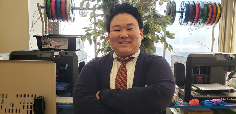 Mr William Lee smiling in front of school 3D printers