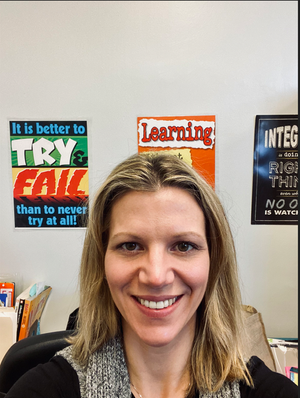 Erica Howard smiling in classroom with motivational posters behind her