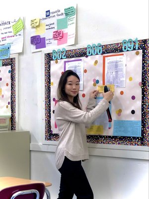 Teacher Evelyn Ng posting materials on a classroom bulletin board