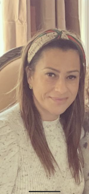 Gina Catania smiling in a white sweater and headband