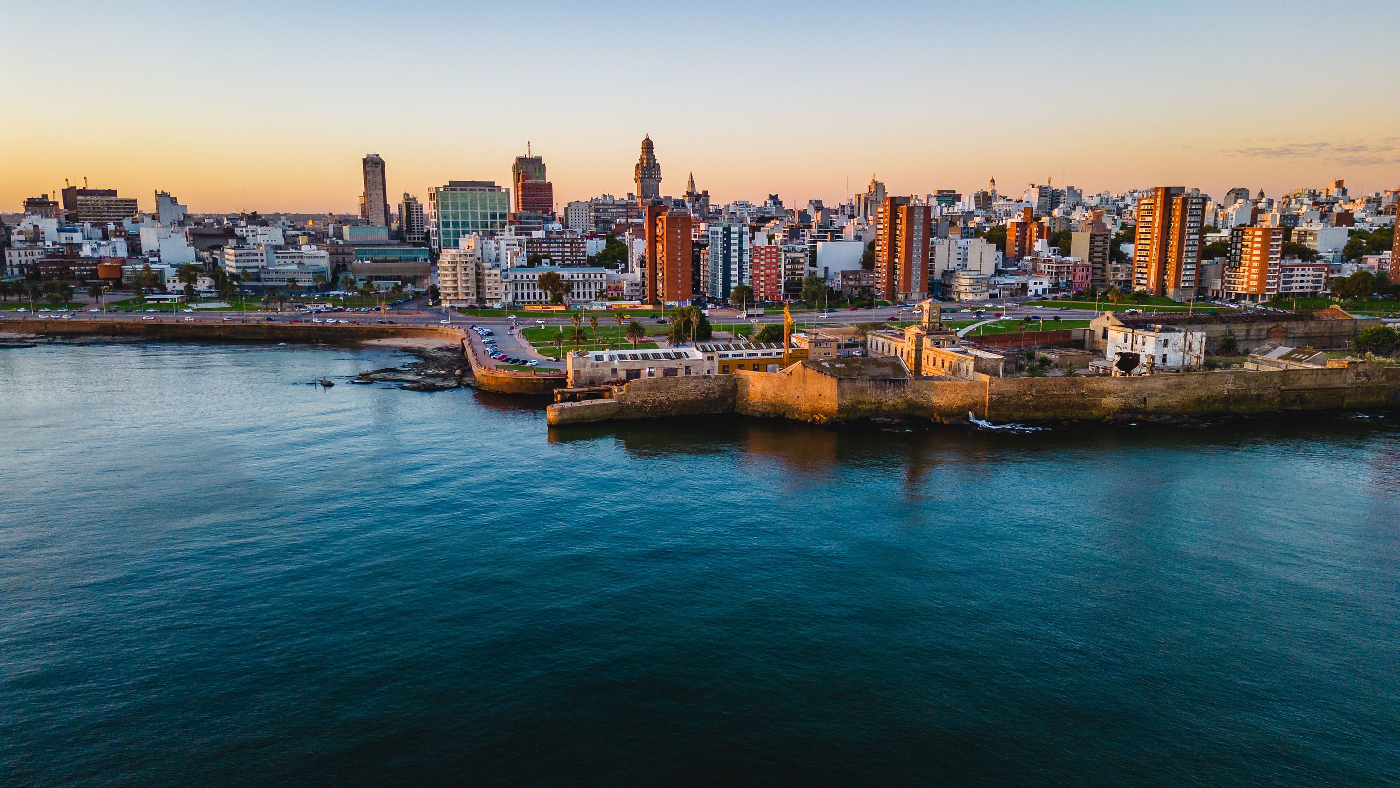 Aerial view of Montevideo, Uruguay, at sunset, overlooking the city's waterfront, historic district and modern skyline, home to Alpadis' new office serving clients across Latin America.