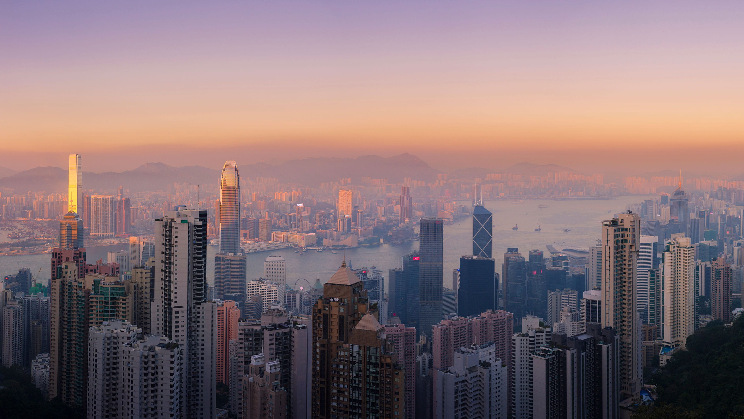 Panoramic view of Hong Kong's Central business district and Victoria Harbour at sunset, illustrating Hong Kong's position as a leading international financial centre and corporate hub for company re-domiciliation and cross-border business.