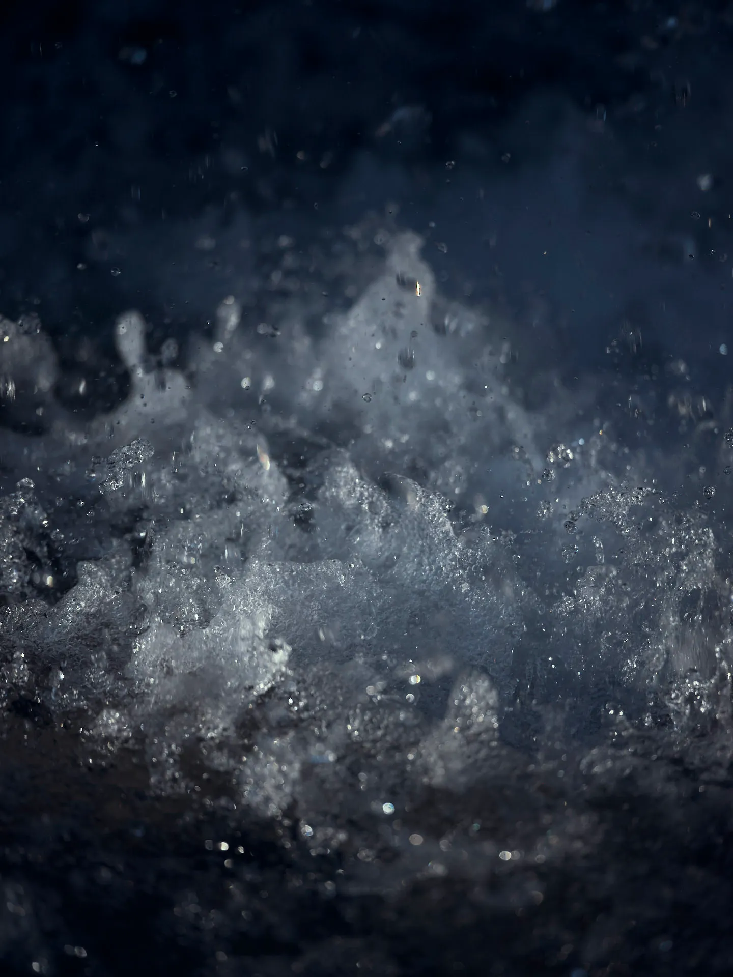 Nahaufnahme von spritzendem und schäumendem Wasser bei dunklem Hintergrund.