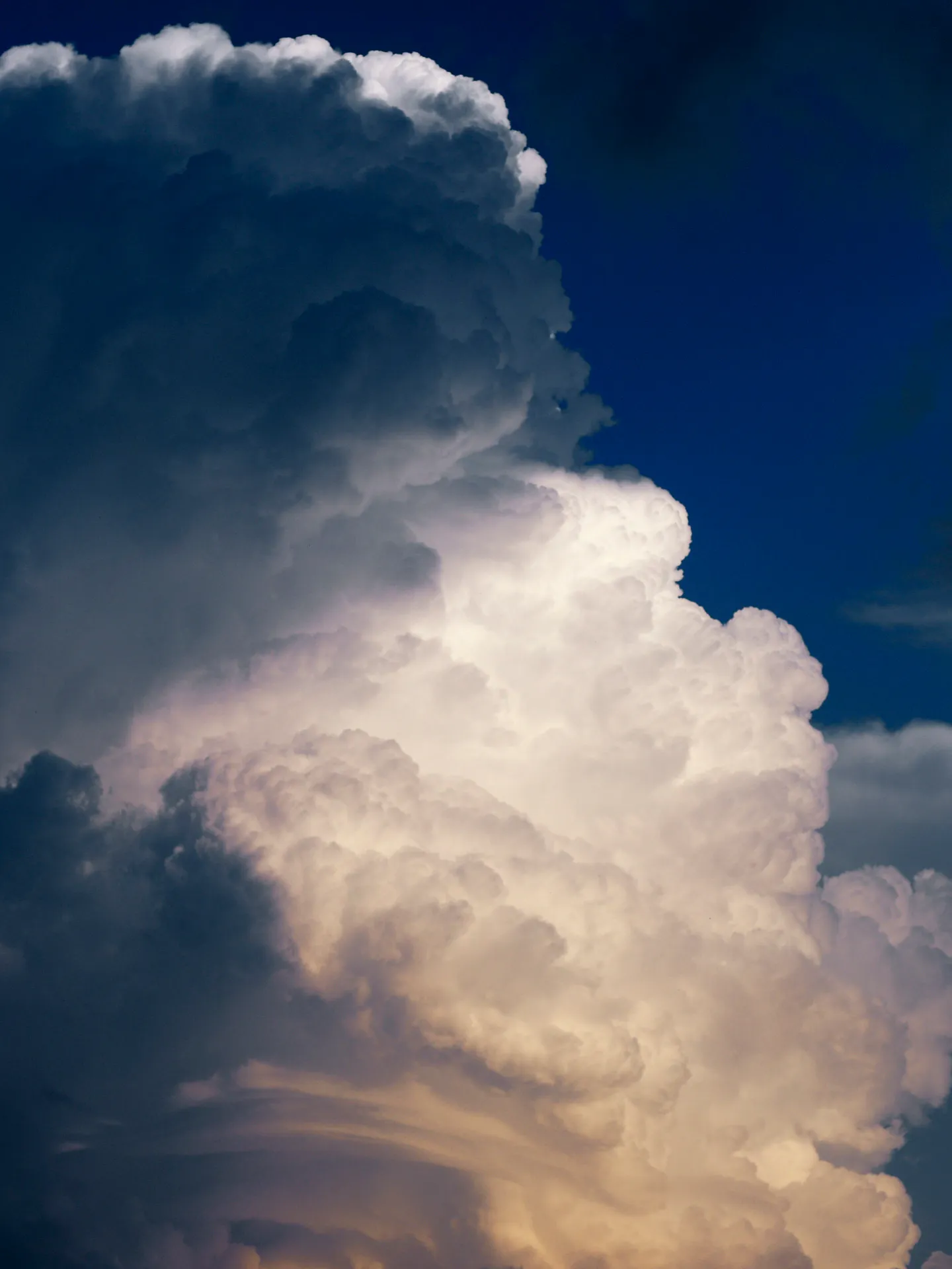 Dramatisch aufgeladene Wolkenformation mit hellen und dunklen Gewitterwolken vor tiefblauem Himmel.