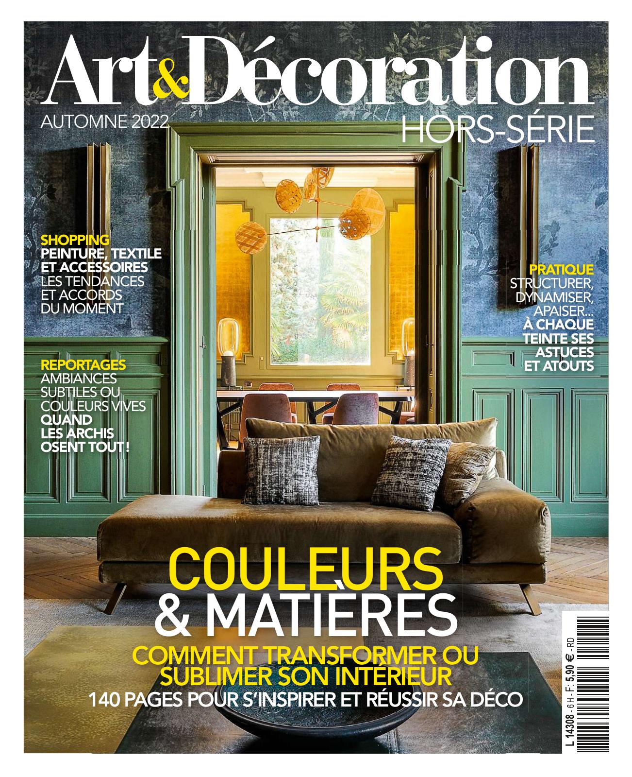  : Couverture du magazine Art & Décoration, hors-série Automne 2022. En image : un salon élégant et coloré avec un canapé vert kaki, deux coussins graphiques, un mur bleu foncé orné de moulures et une grande ouverture encadrée de boiseries vertes donnant sur une salle à manger jaune doré. Des suspensions dorées en forme de sphères flottent au-dessus d'une table entourée de chaises.