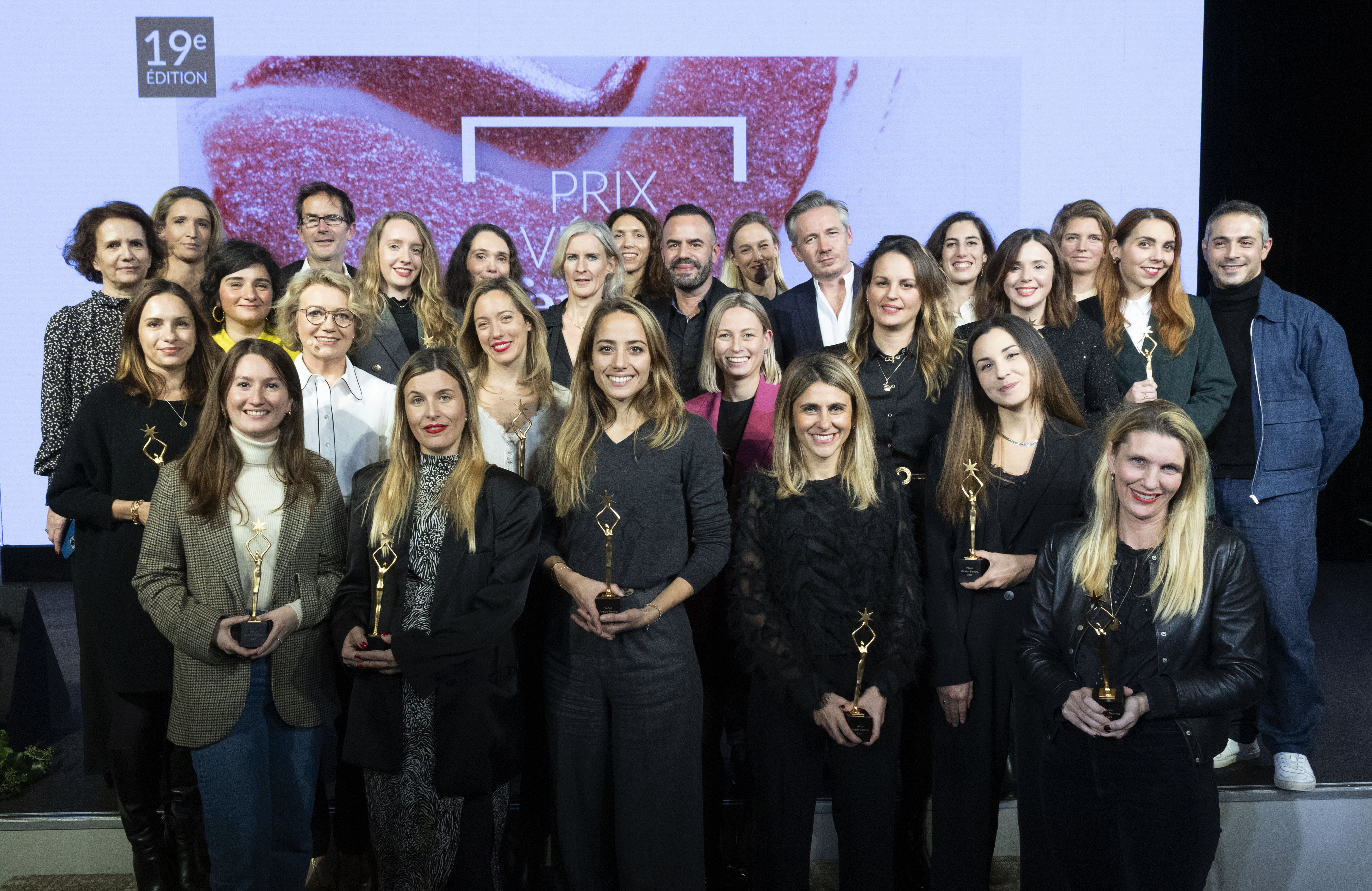 Photo de groupe rassemblant une trentaine de personnes, principalement des femmes, tenant des trophées en main, sur fond d’écran affichant “19e édition - Prix Vénus Femina”.