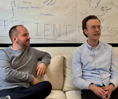Portrait de Johan et Paul ensemble devant un tableau blanc couvert de notes manuscrites