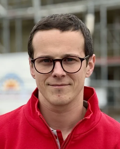 Porträt von Nico Fritzmann in roter Jacke auf einer Baustelle