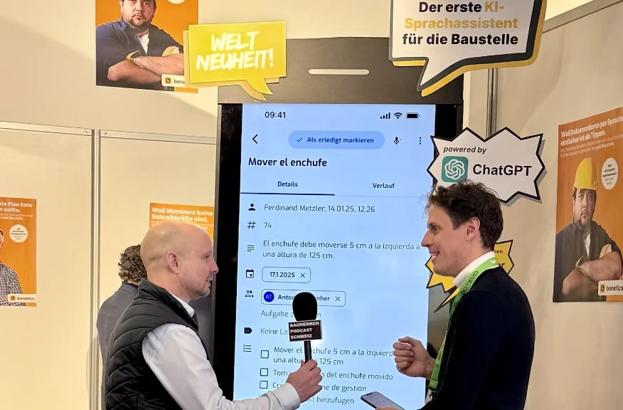 Interview an einem Messestand: Ein Mann wird vor einem großen Bildschirm mit der Benetics-App und einem „powered by ChatGPT“-Hinweis interviewt