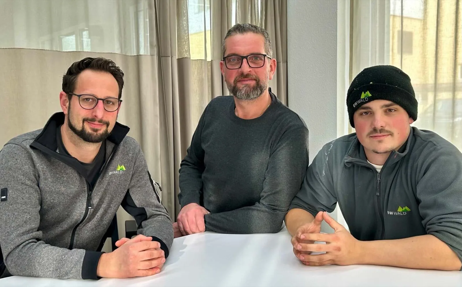 Tres empleados de ewWALD sentados juntos en una mesa