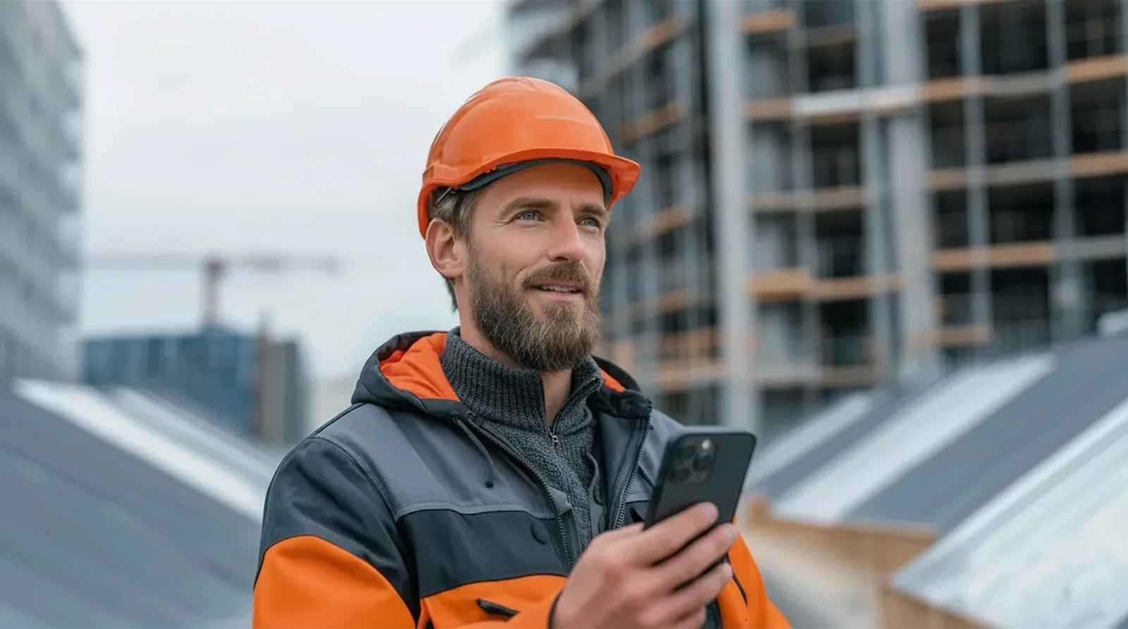 Bauleiter mit Smartphone auf einer Baustelle.