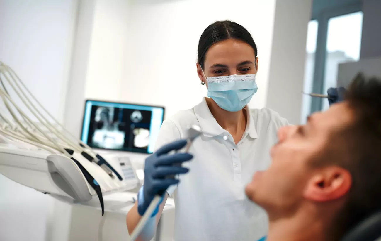 Female dentist performing check up on male patient.