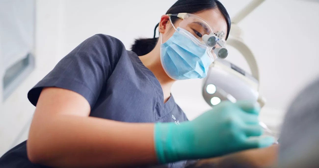 Dental hygienist wearing loupes and gloves carrying out a deep clean treatment on a patient at Kingfisher Dental.
