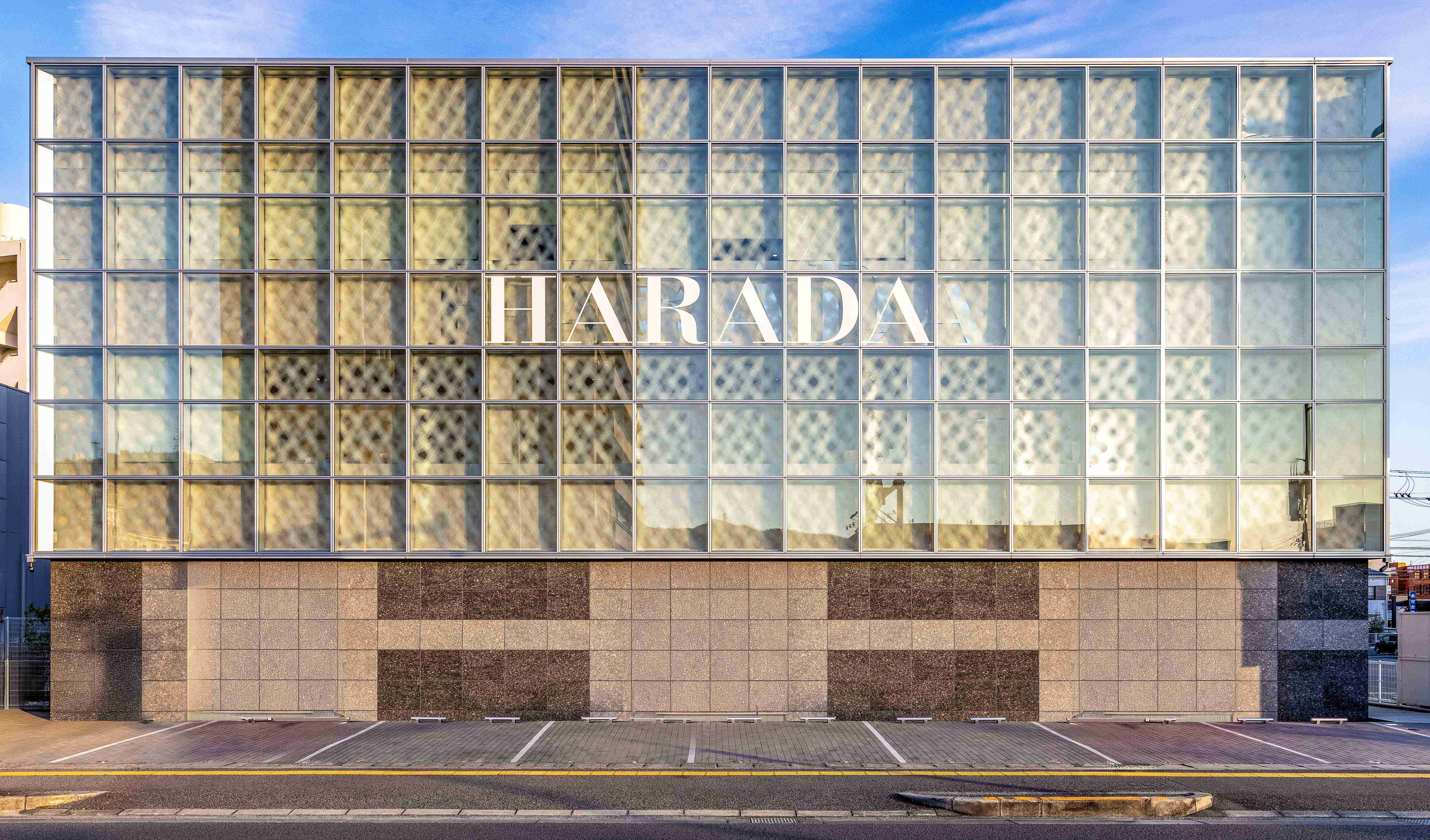 Full elevation of Harada building with i-Mesh textile façade showing modular grid and light diffusion