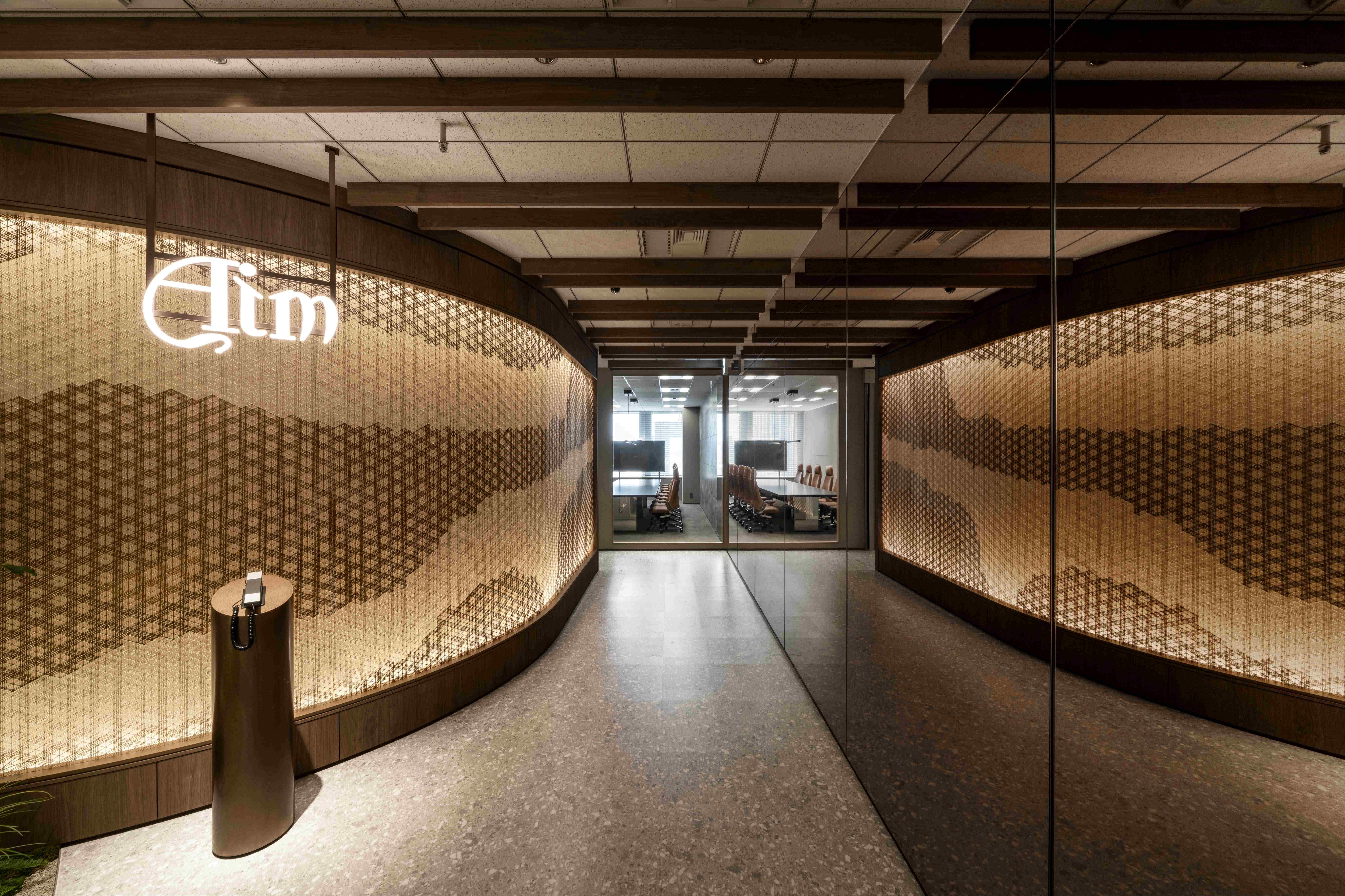 Curved i-Mesh wall with backlit Kumiko-inspired pattern at the Aim office entrance, Tokyo