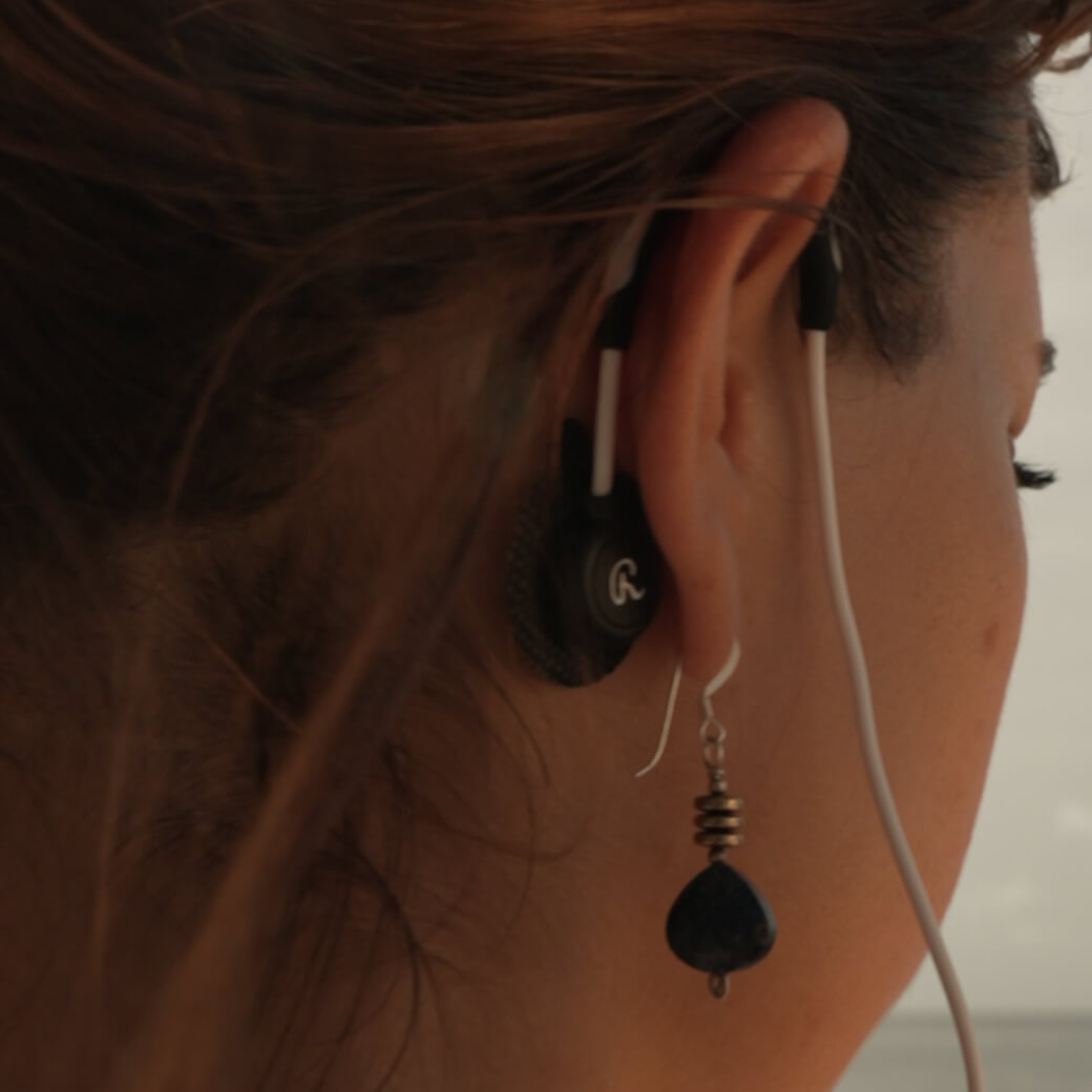 A zoomed in image behind the ear of a woman showing the ear hooks attached to the bone behind the ear