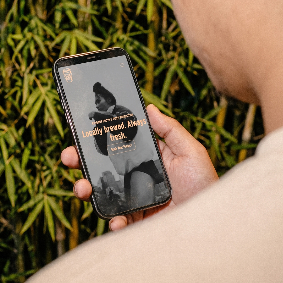 Person holding a phone showing the Half Full Media site, with the headline "Locally brewed. Always fresh." over a black and white photo.
