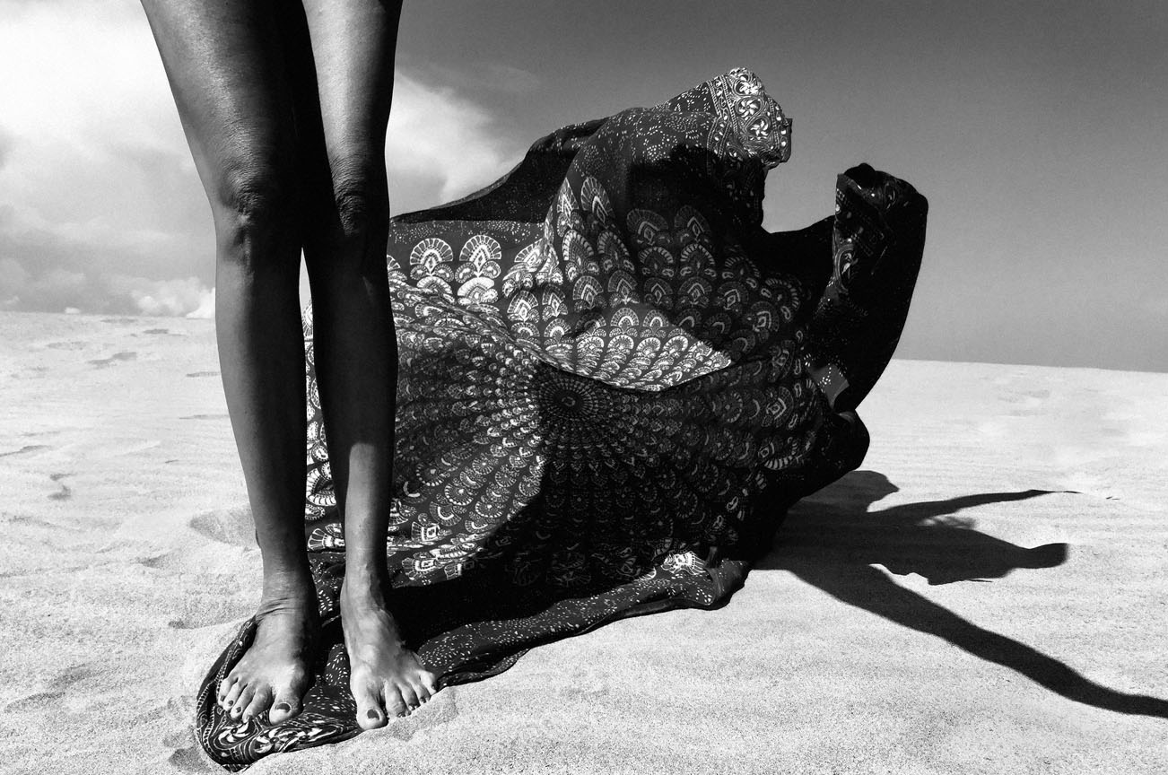 Gambe e tessuto decorativo con motivi intricati sulla sabbia deserta