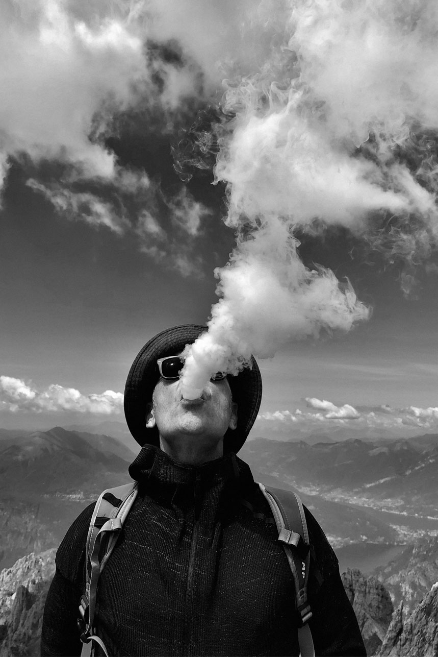 Escursionista che emette fumo contro un paesaggio montuoso in bianco e nero