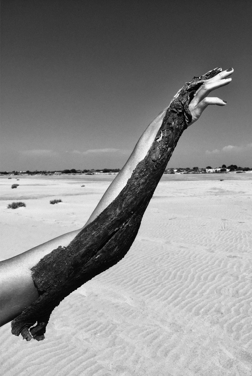 Braccio contorto e carbonizzato su sabbia desertica in bianco e nero