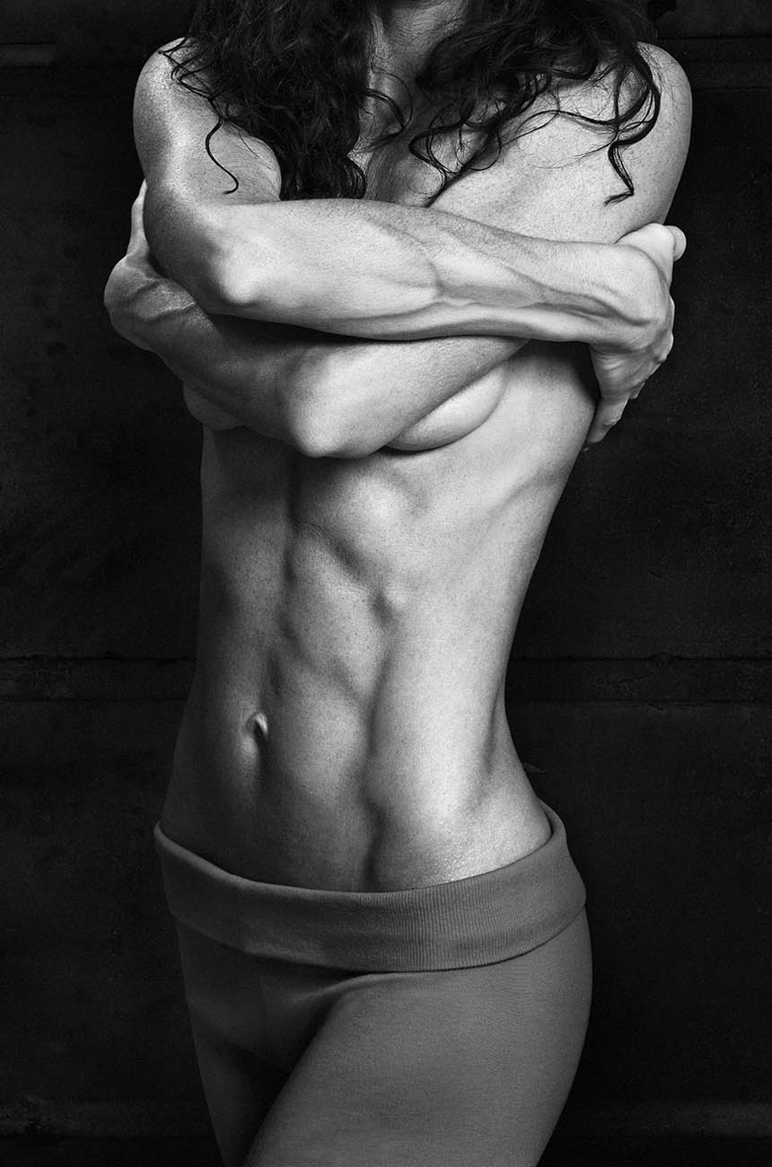 Corpo femminile in bianco e nero che si abbraccia, muscoli definiti